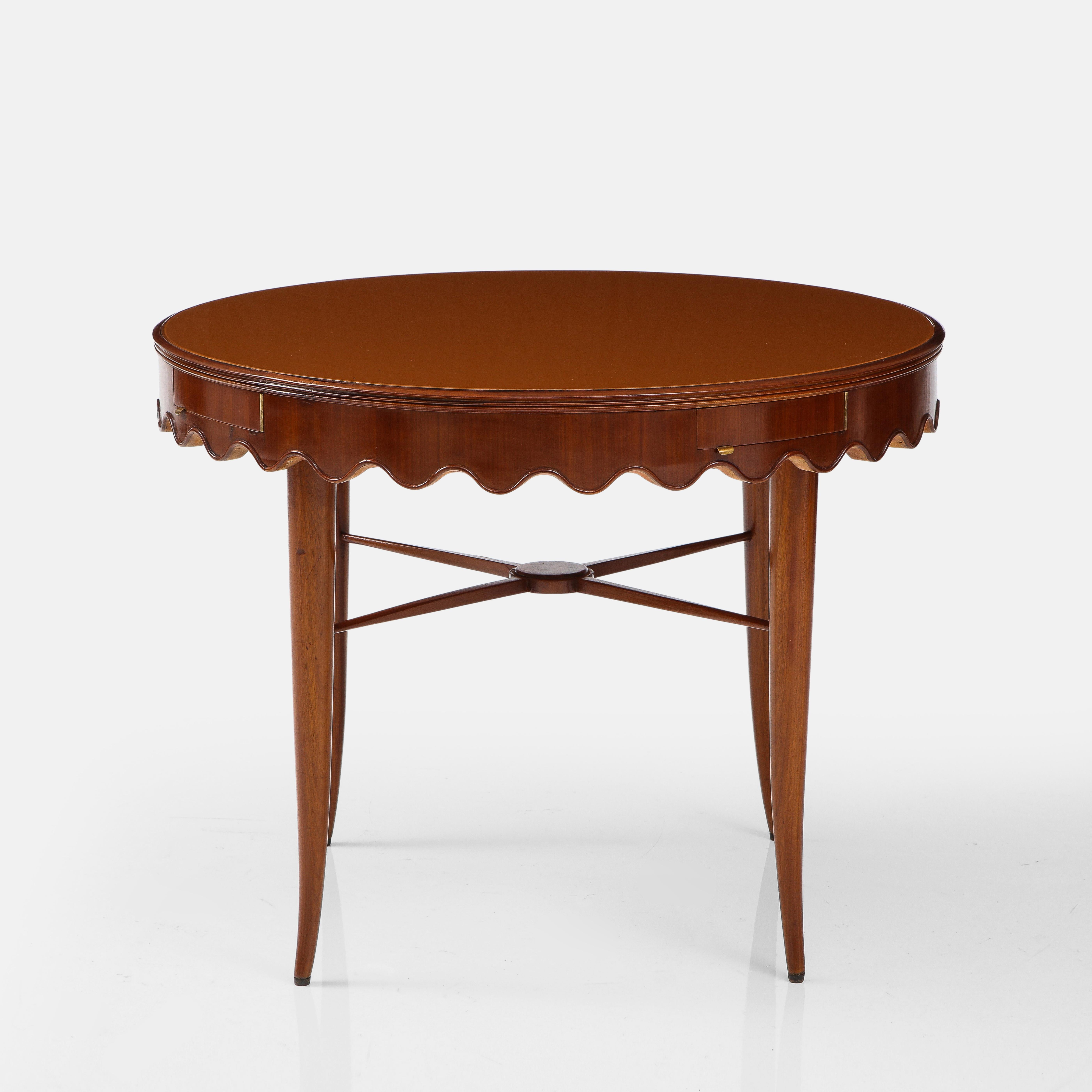 Rare and exquisite Paolo Buffa center or game table in walnut composed of inset reverse painted or eglomisé glass top with scalloped apron, four small drawers, stretcher with central medallion, and slightly splayed saber legs, Italy, 1940s. This