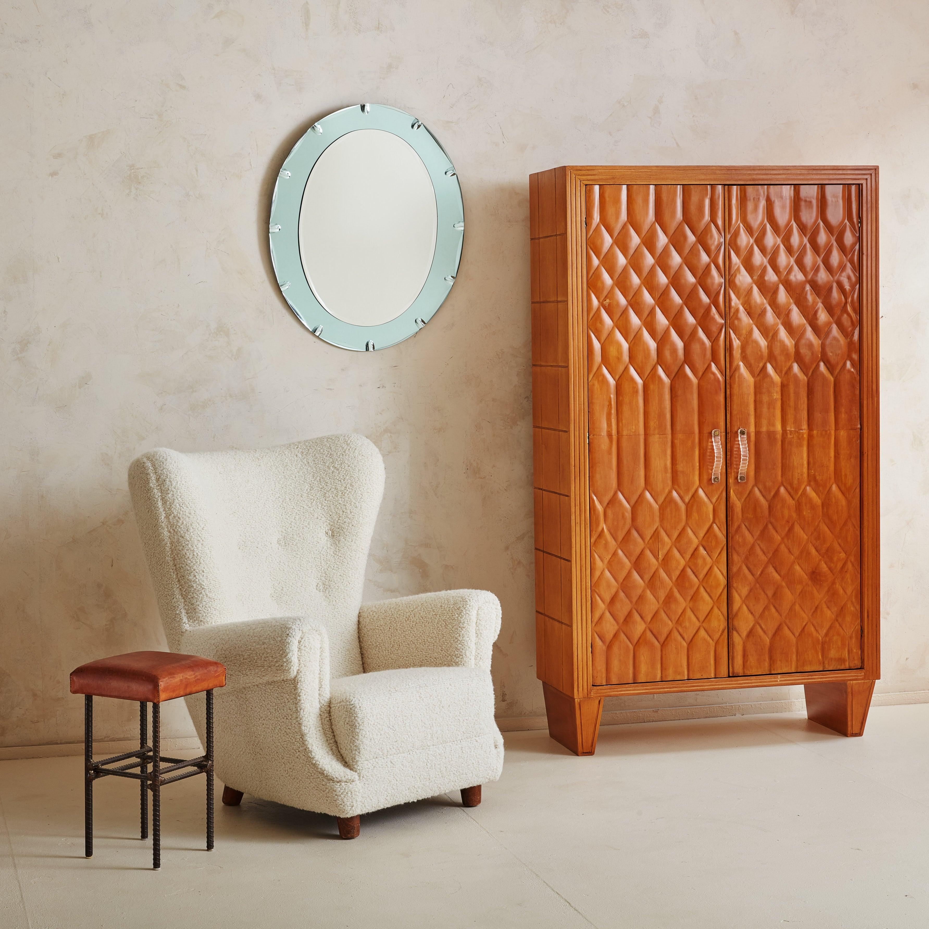 An exquisite 1950s armoire cabinet in the style of Italian architect and furniture designer Paolo Buffa. The monumental silhouette is composed of waxed wood in a rich, cherry hue and features sculptural Murano glass handles secured with brass