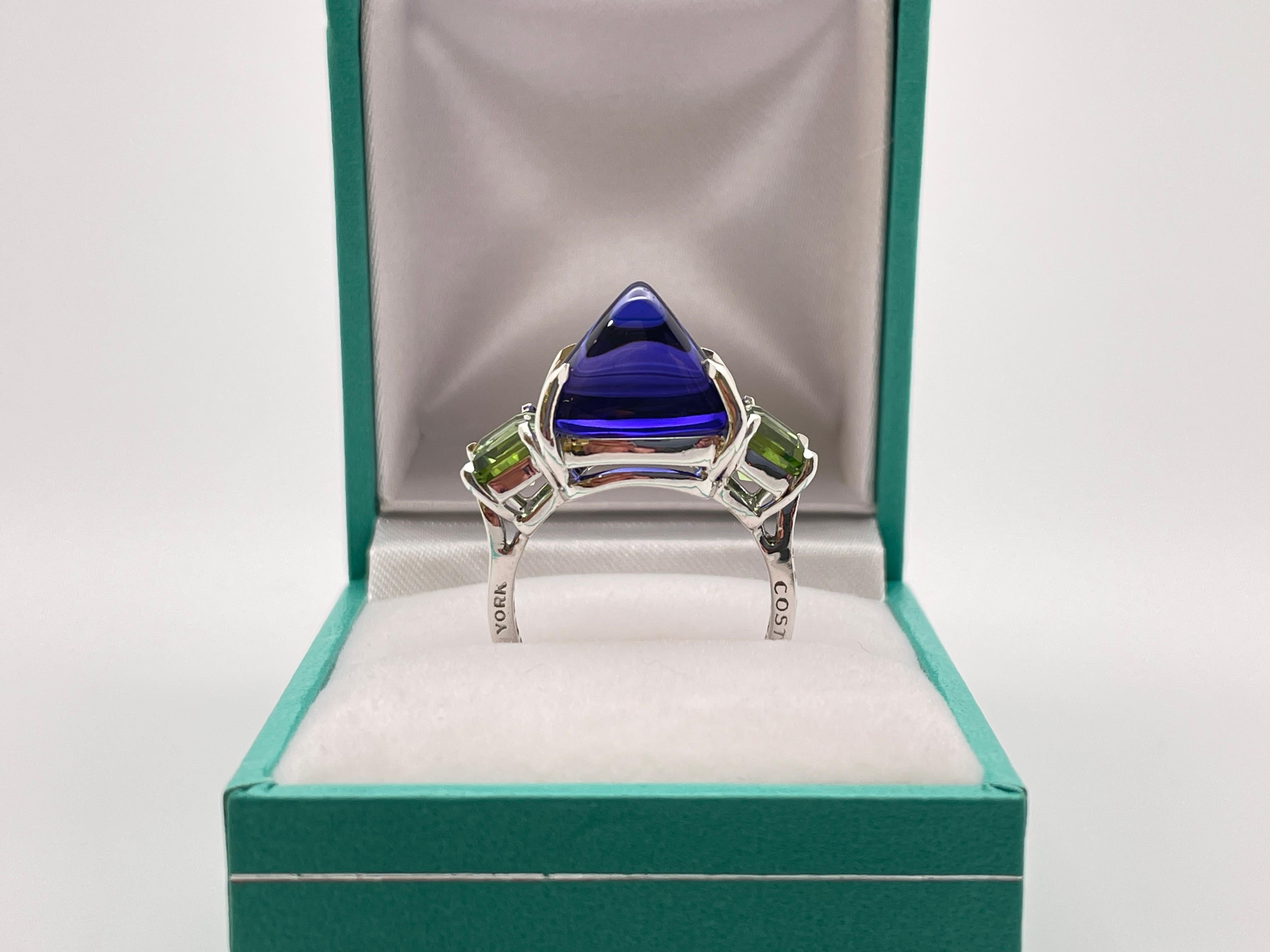 Magnifique bague Paolo Costagli en or blanc 18 carats, diamants, tanzanite et tourmaline. Au centre, un énorme billion de tanzanite naturelle taillée en cabochon, de couleur bleu-violet rafraîchissante, pesant environ 8-10 CT. Chaque côté est serti