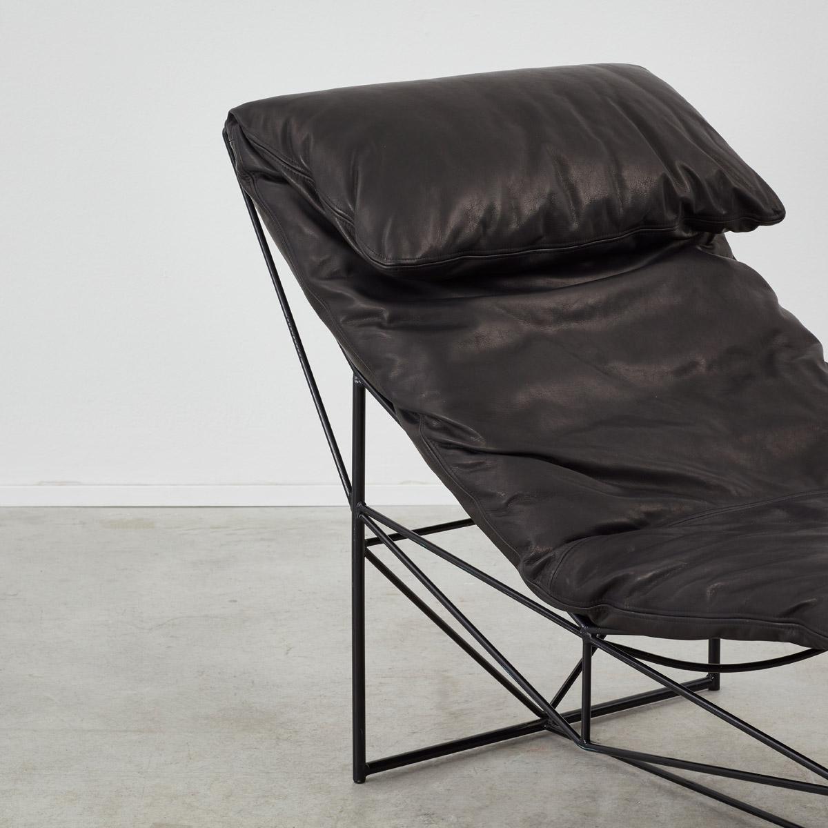 Sculptural chaise longue by Paolo Passerini. The frame is formed of black lacquered iron rods joining at angels, creating striking triangular shapes. A large white cushion lines the top of the chair.