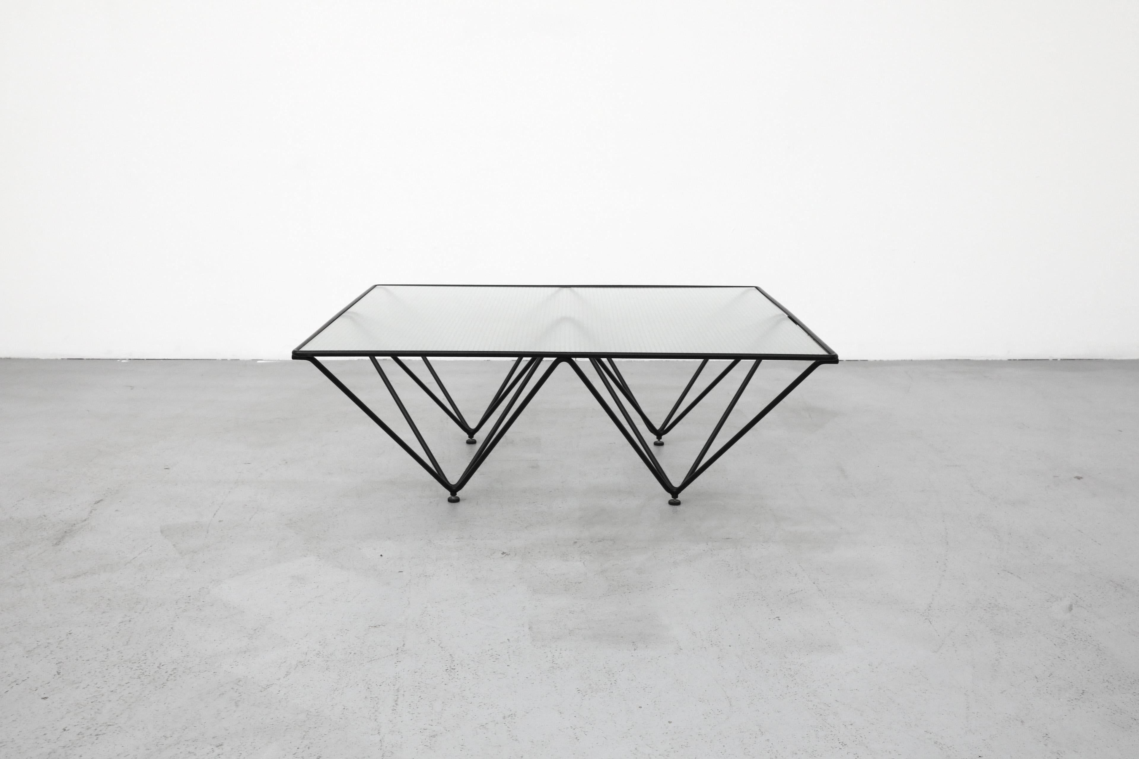 Italian Mid-Century square glass top coffee table with black pyramid frame. Designed in the style of Paolo Piva, this table features an enameled metal architectural frame with adjustable feet. Inset glass top is smooth on top and grid textured on