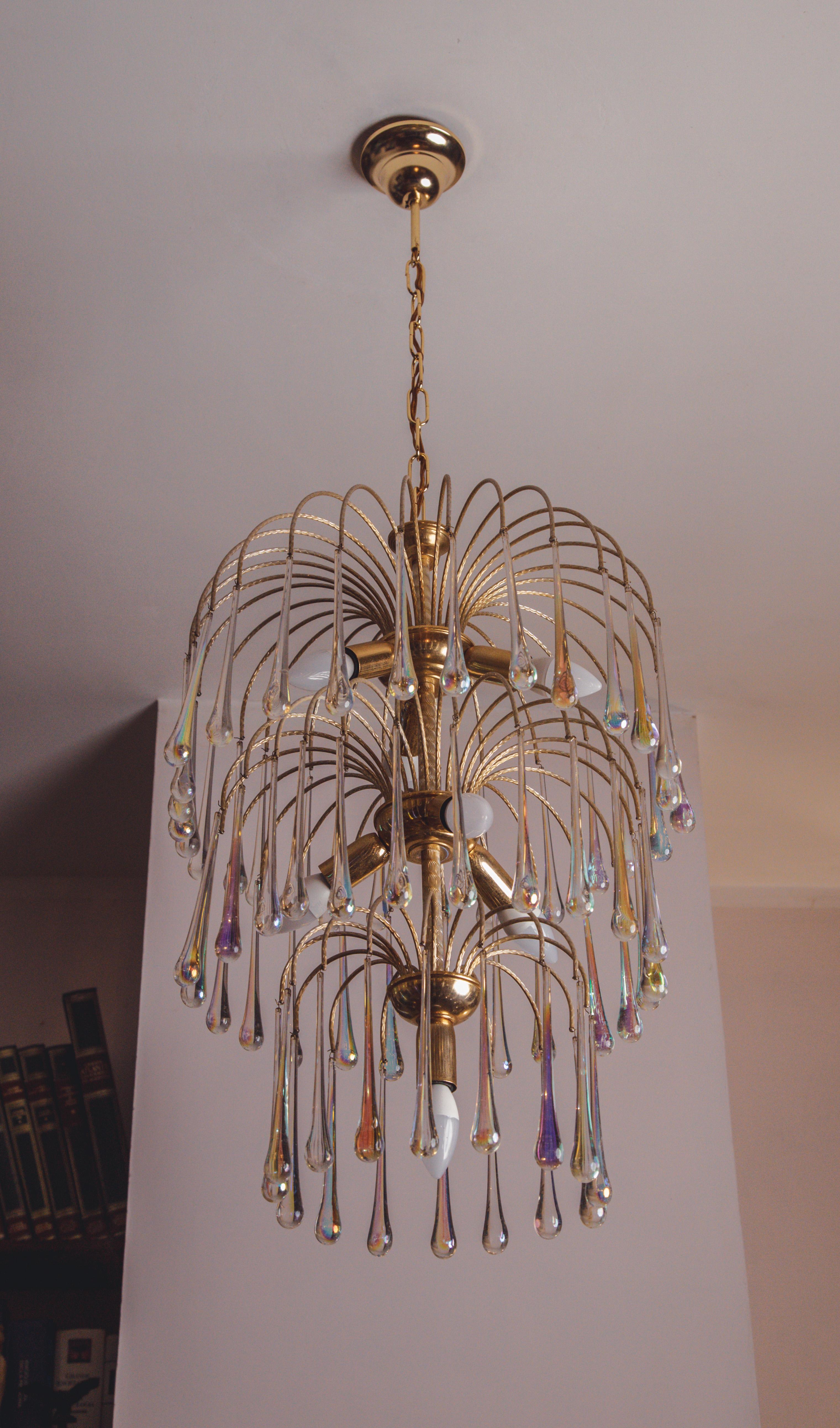 Splendid Murano chandelier attributable to Paolo Venini's 'Cascata'.
The structure of the chandelier consists of 3 cascades full of iridescent drops that cascade downwards.
The peculiarity of this glass is that it takes on a colour according to