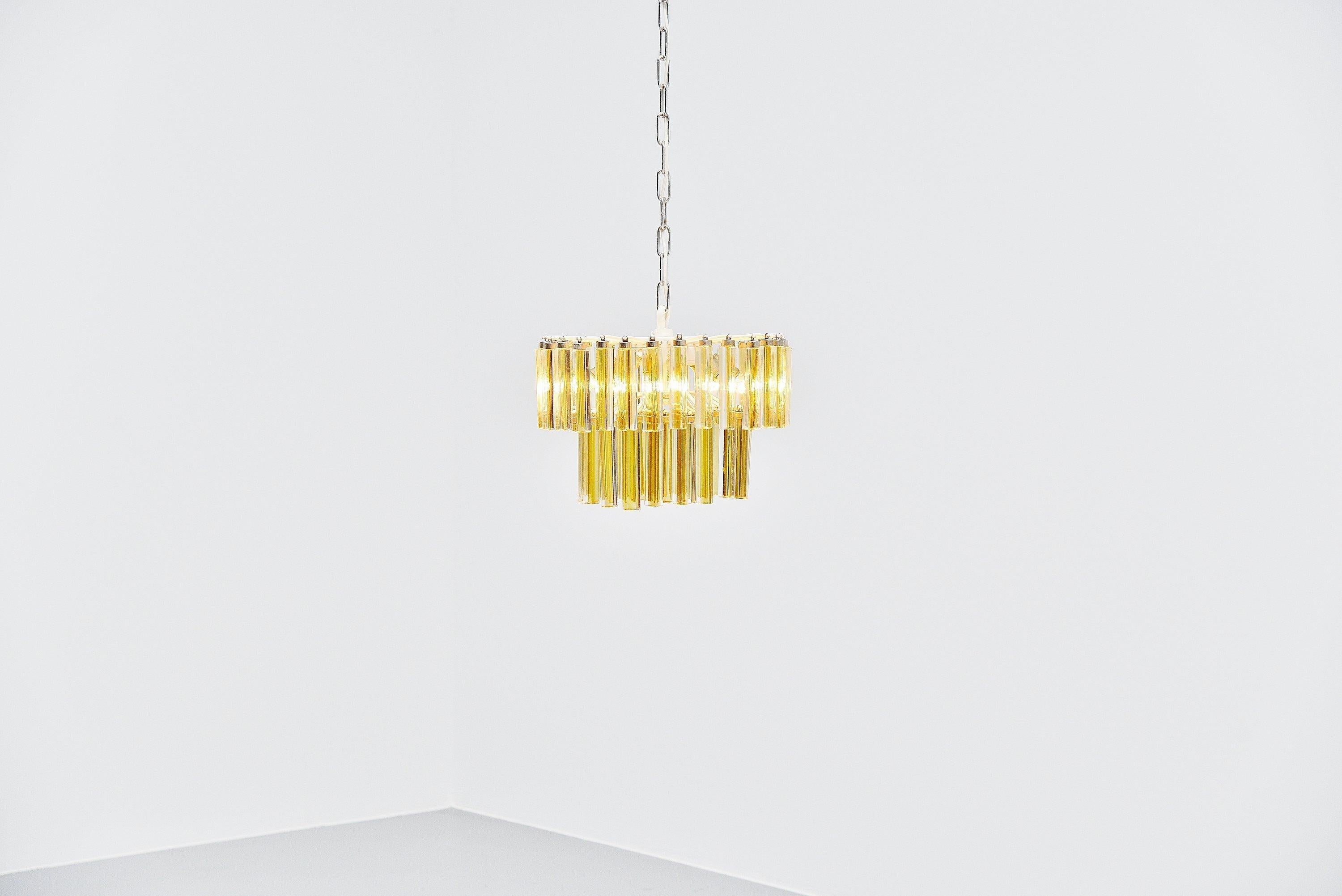 Decorative chandelier designed by Paolo Venini and manufactured by Venini, Italy 1960. The lamp has a metal white painted frame which holds 55 crystal glass pegs in clear and yellow glass, the lamp gives very nice warm light when lit. Lamp uses E14