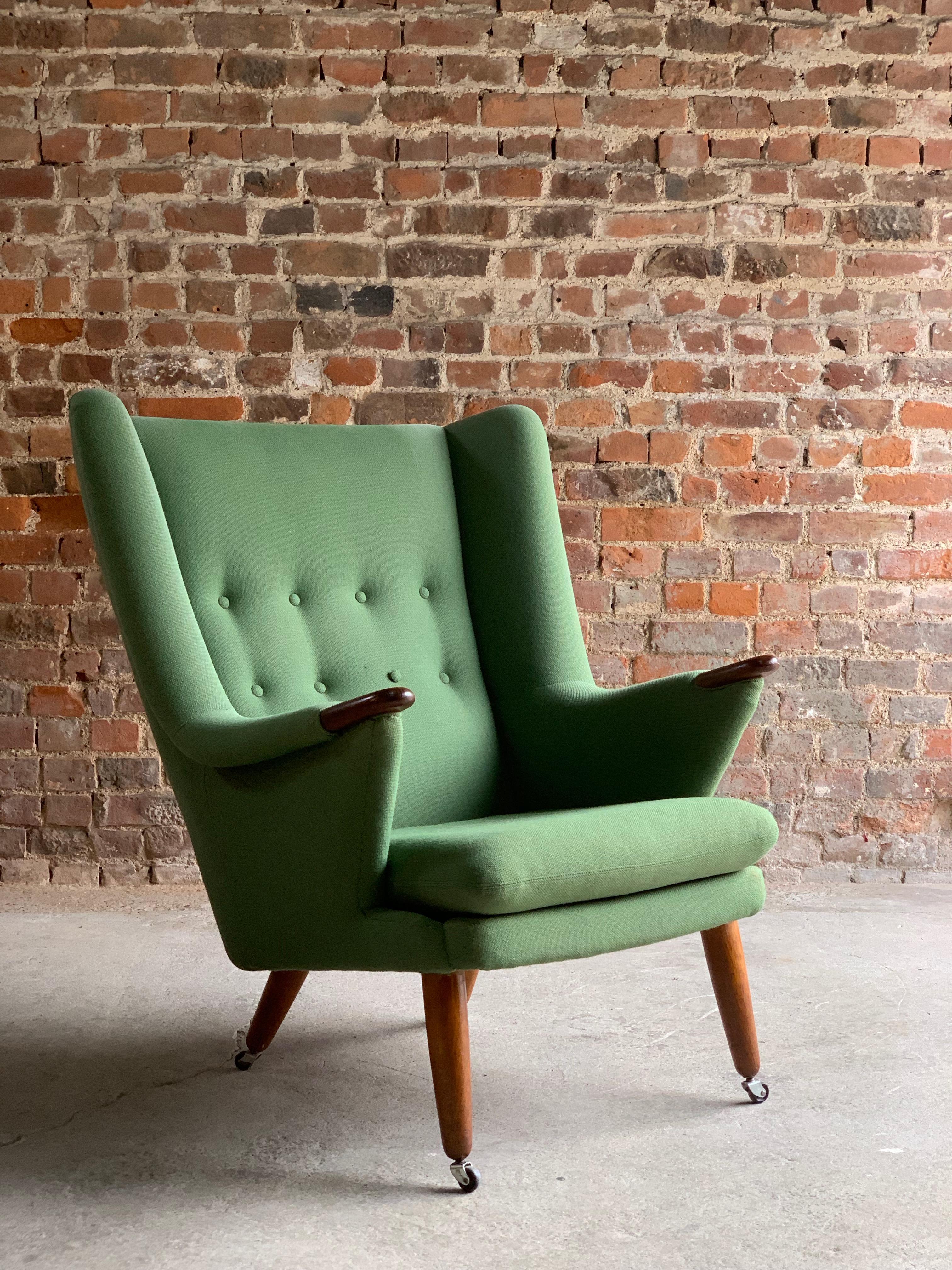 Midcentury Danish ‘Papa Bear’ armchair, circa 1950s, the pea-green fabric upholstered wing armchair, having a buttoned back, with oak finished arm rests paws on conforming turned and tapering supports to castors.

  