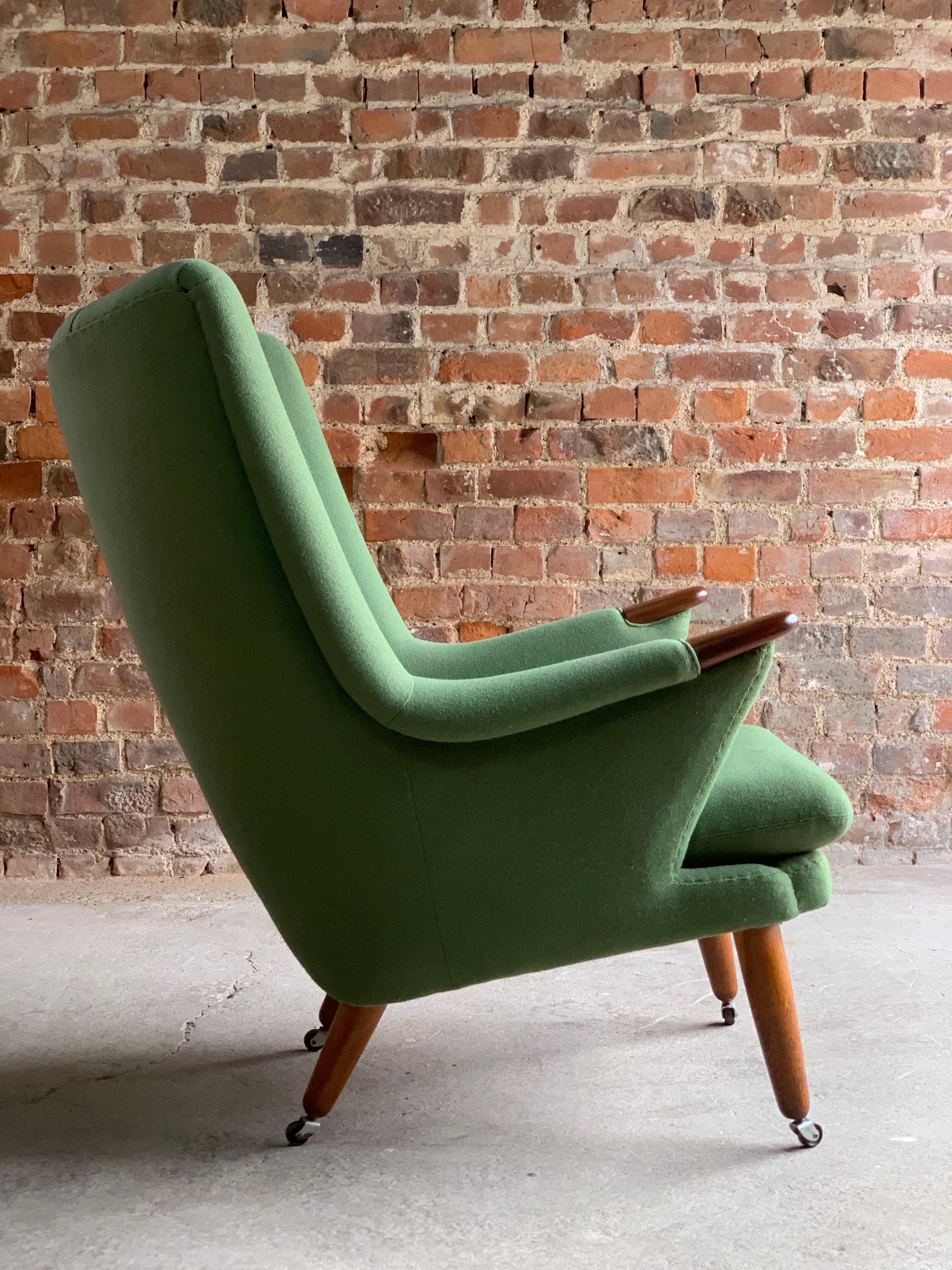 Midcentury Danish ‘Papa Bear’ armchair circa 1950s, the pea-green fabric upholstered wing armchair, having a buttoned back, with oak finished arm rests paws, on conforming turned and tapering supports to castors.

  