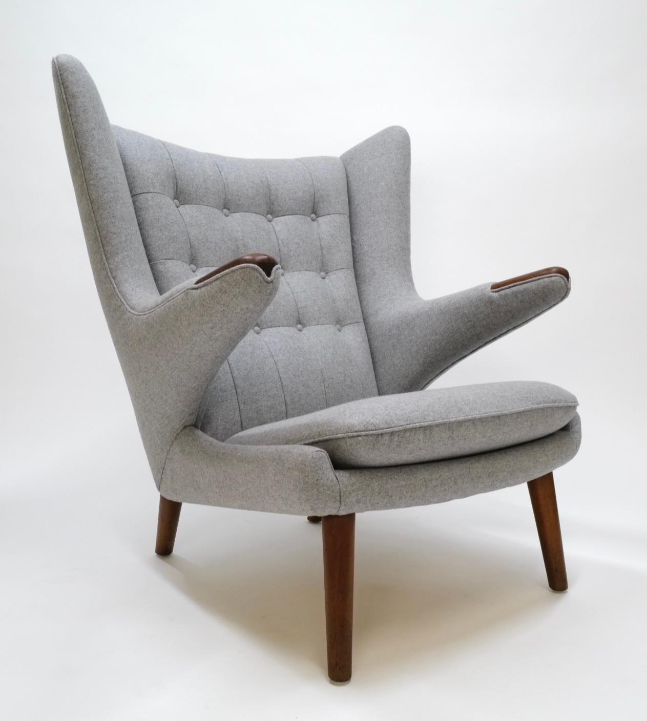 The Papa Bear Chair, a classic design by Hans Wagner, showcases timeless elegance with its iconic mid-century modern silhouette. This particular piece has been meticulously reupholstered by skilled professionals using Kravets heather grey wool