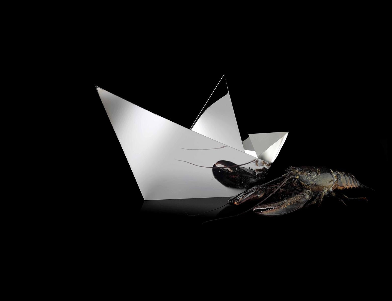 Paper Boat ist ein Tafelaufsatz aus dünnen silbernen Metallschichten, die meisterhaft gebogen wurden, um die Form eines Origami-Papierschiffs nachzubilden. Dieses von Aldo Cibic für Paola C. entworfene Objekt ist eine echte Skulptur, raffiniert und