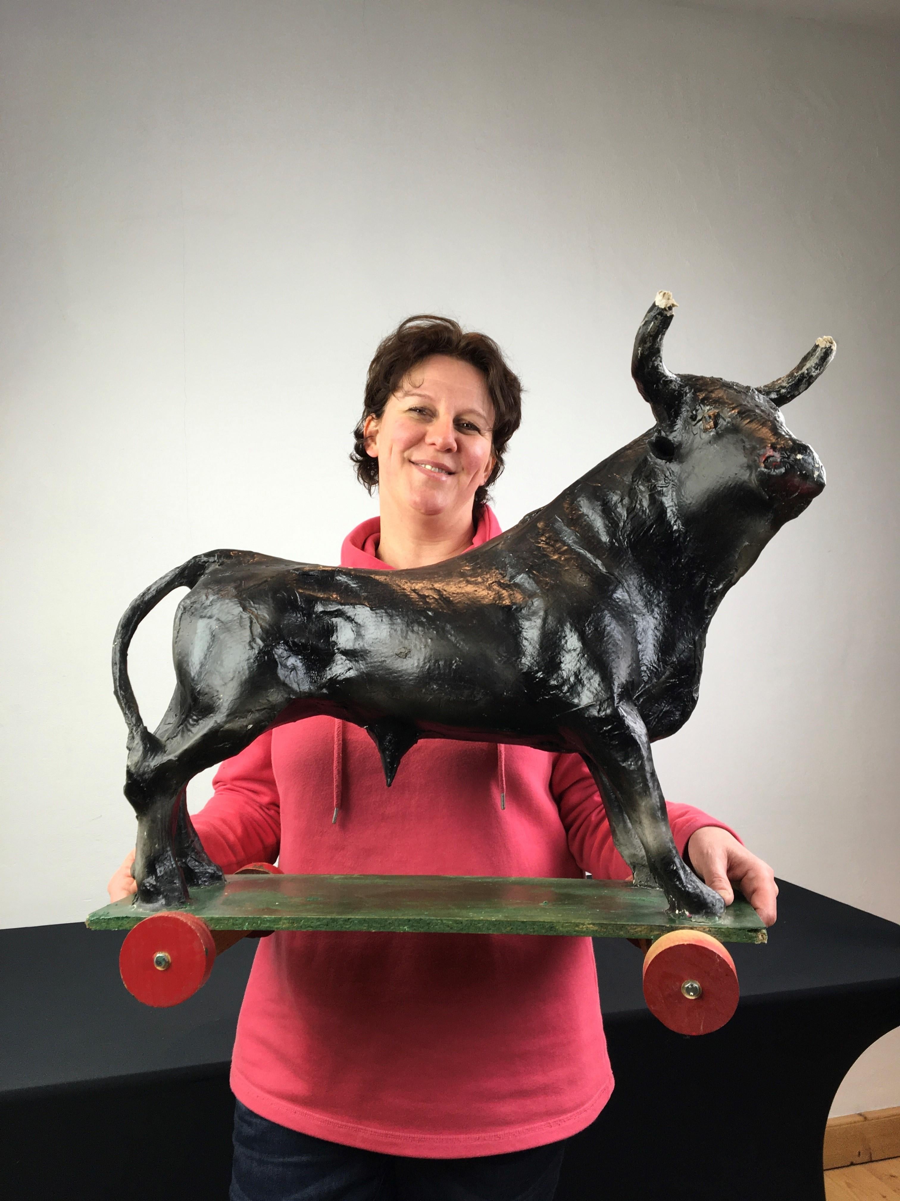 Paper Mache bull statue on wheels, bull animal on wheels.
A vintage paper mache toy on wooden plate with wheels.
Vintage toy - pull toy on wheels - collectable toy - collectible animal. 
This impressive black bull is a decorative item to place in
