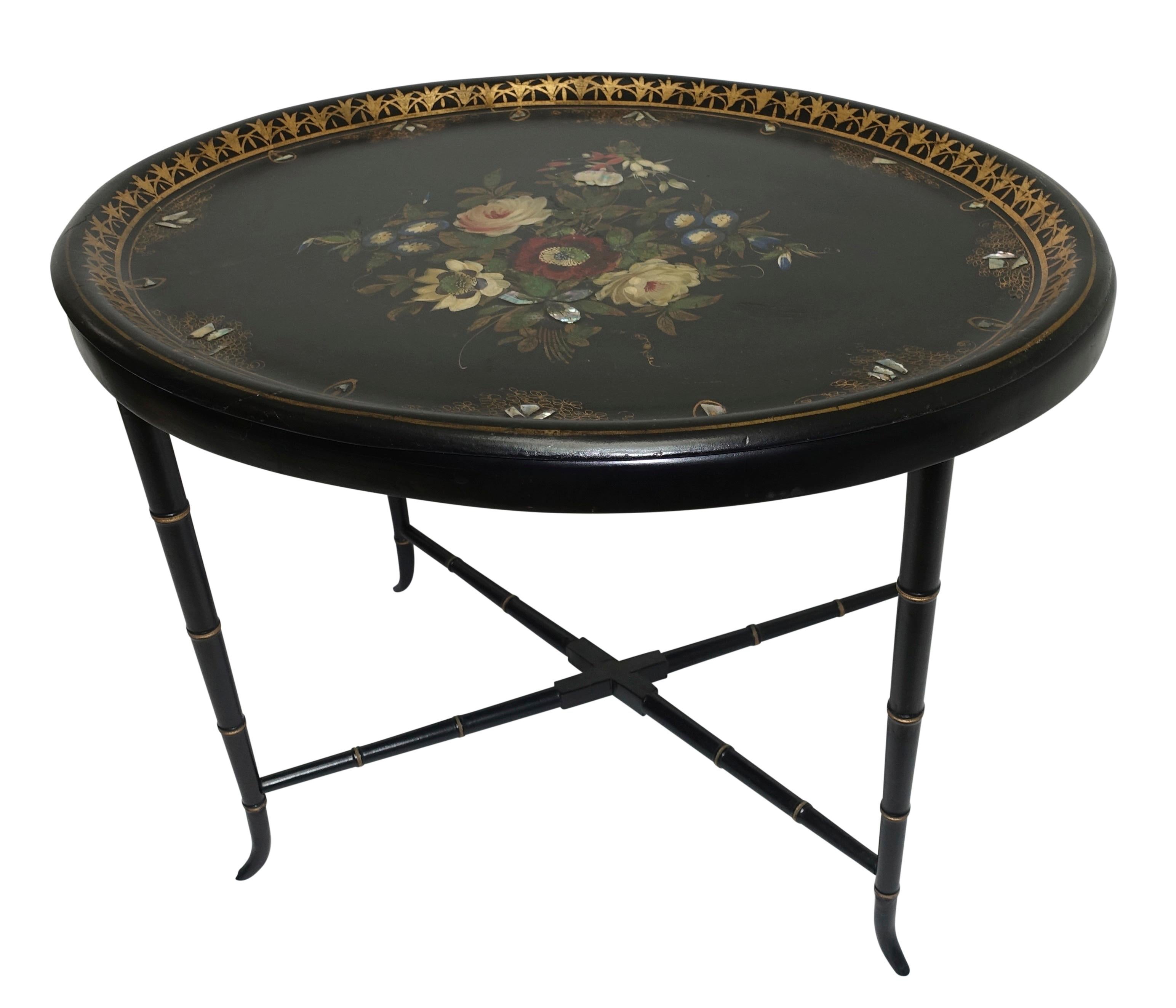 Lovely oval black papier mâché tray on a later stand, having hand painted flowers, mother of pearl inlay and gilt painted banded border. The Stand with faux bamboo legs, England, circa 1860.