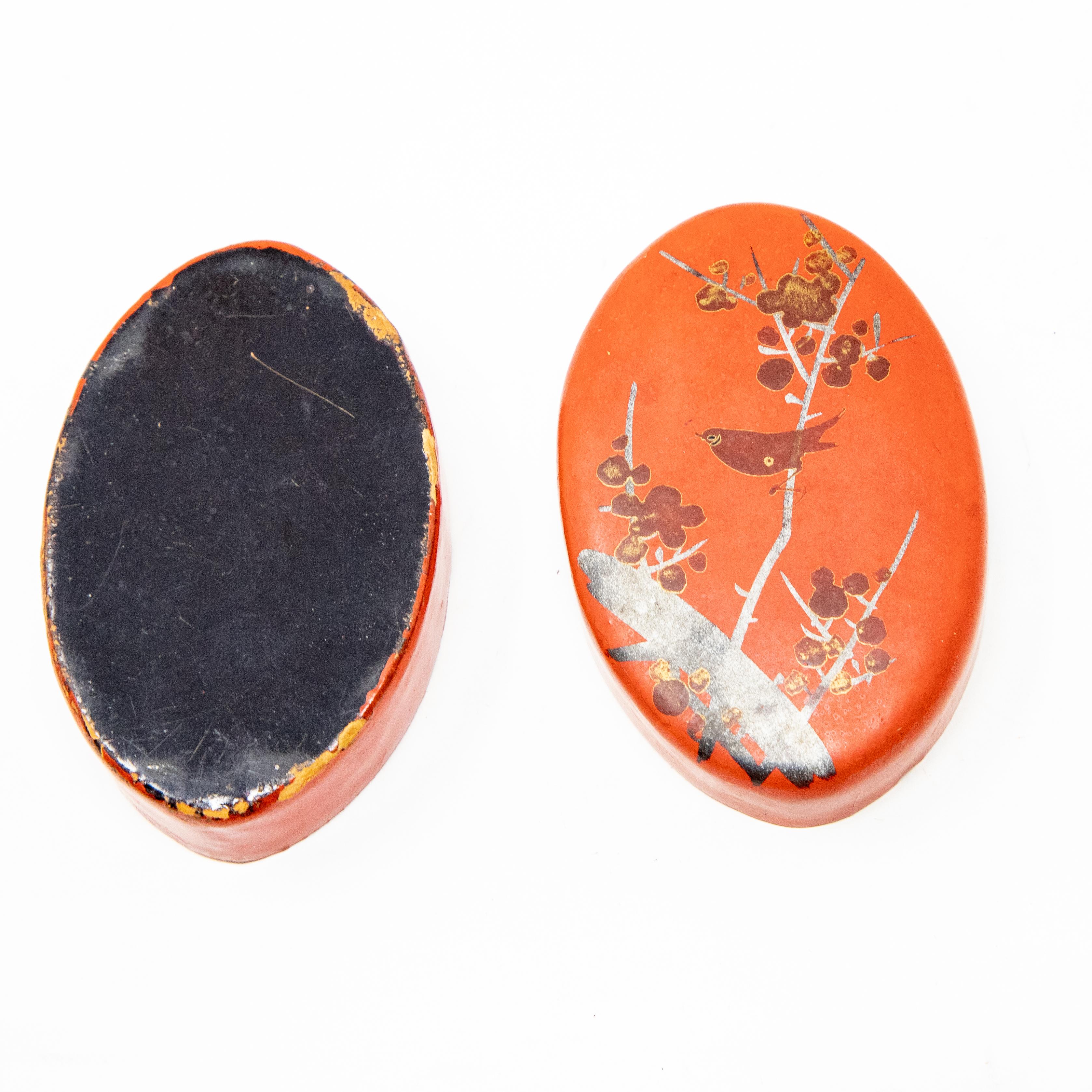 Offering this gorgeous red lacquer paper mâché pillbox. Hand painted in red lacquer with black and gold foliate and bird motif. Opened on the inside is black lacquer, and the bottom is black lacquer as well.