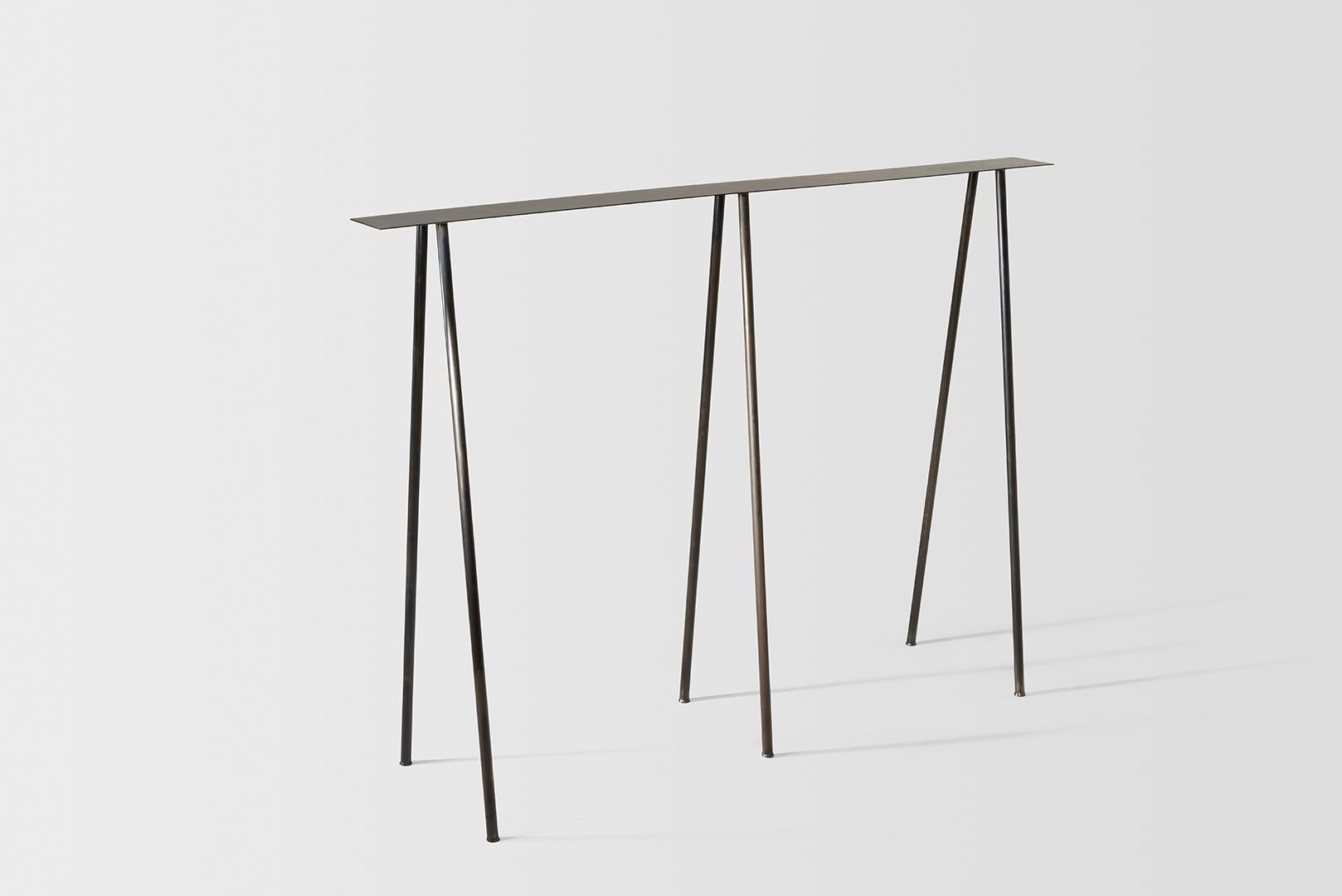 Where metal implies sturdiness, and calls for strong industrial motifs, the I/ the H, the beam / the cross, the Paper Table is a play on our own sense of balance. 

It questions the thinness of both surface and structure, in order to reach their