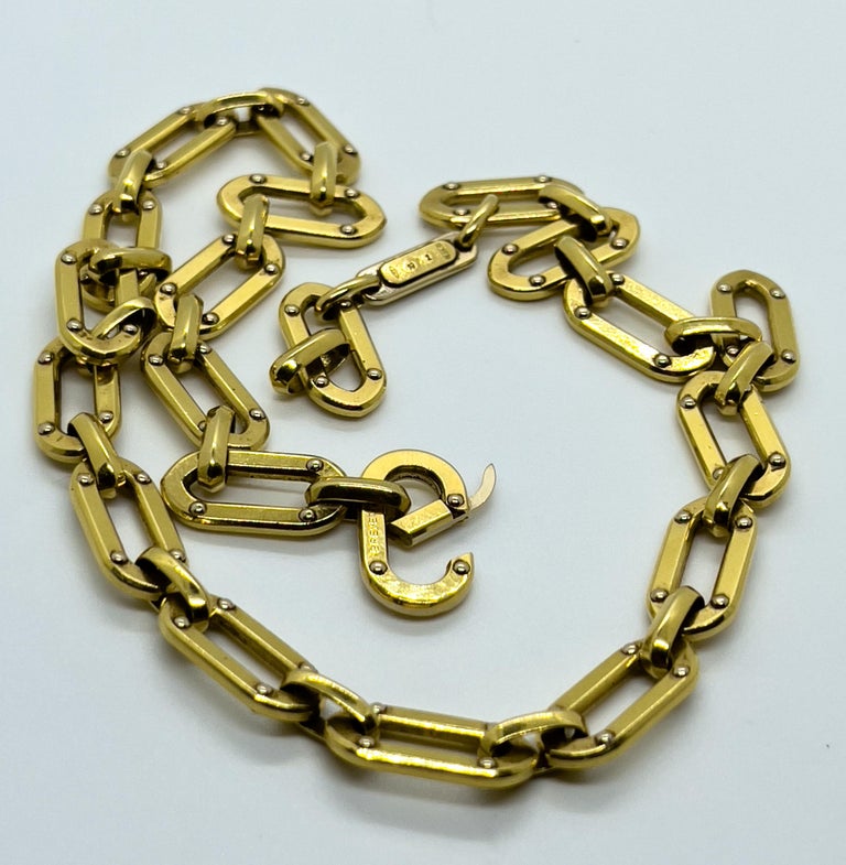 A paperclip solid necklace made of 18K yellow gold. Each oval chain link is decorated with four dots on the both sides. This bold golden necklace is composed of 20 links + a locker. Also next to the locker there is an oval plate signed on the one
