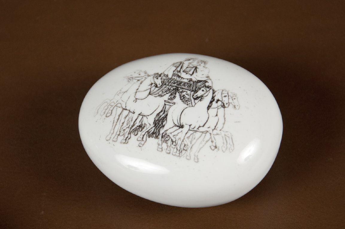 Porcelain paperweight printed with two figures in a chariot pulled by six horses. Marked Fornasetti Milano Made in Italy on the underside. 

