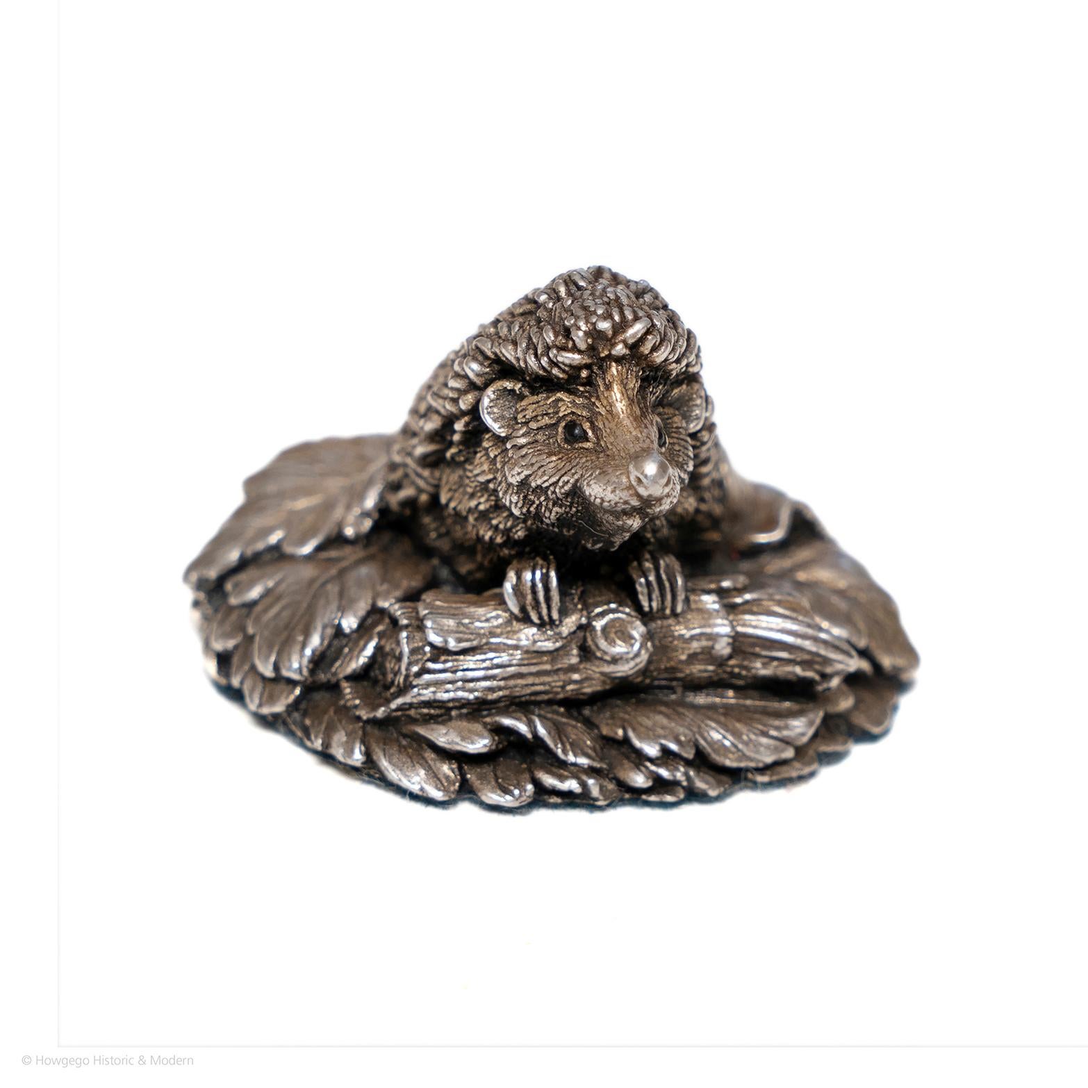 A charming small silver desk accessory or paperweight. Birmingham 1977. 

Modelled as a hedgehog with his front feet resting on a log on leafy ground looking up. Commemorative piece inscribed with the initial 'CA' and the date '1991. Silver assay