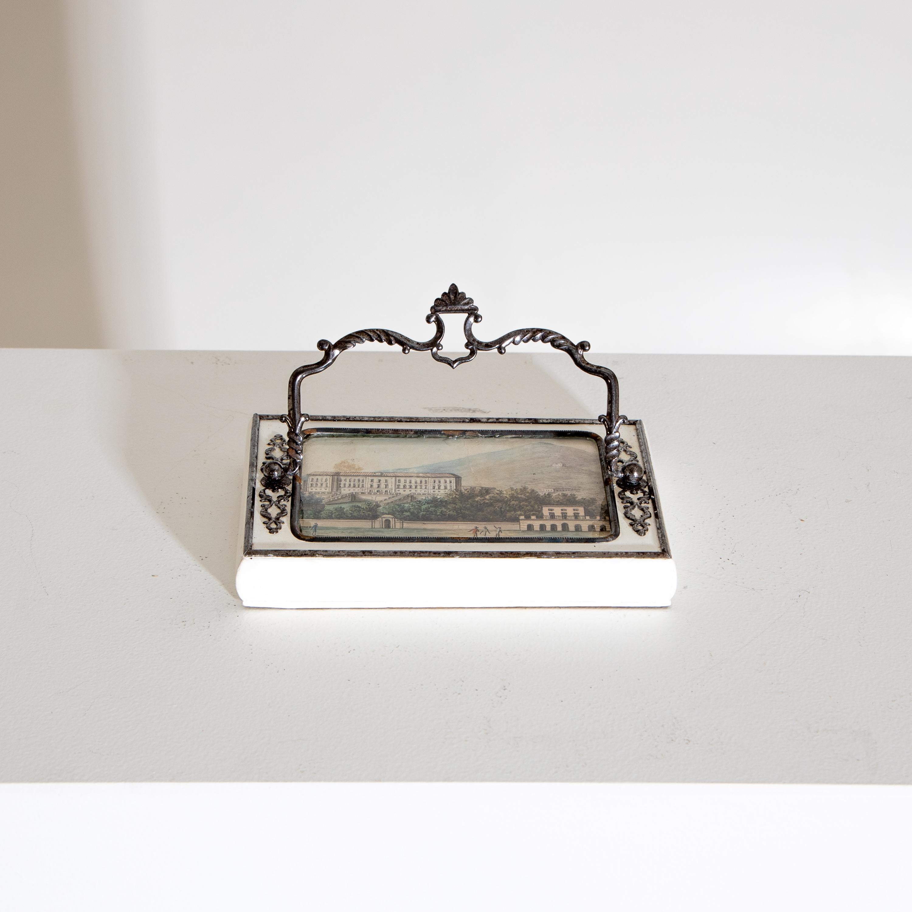 Rectangular white lacquered paperweight with silver-plated fittings and handle and polychrome city view on cardboard, framed behind glass.