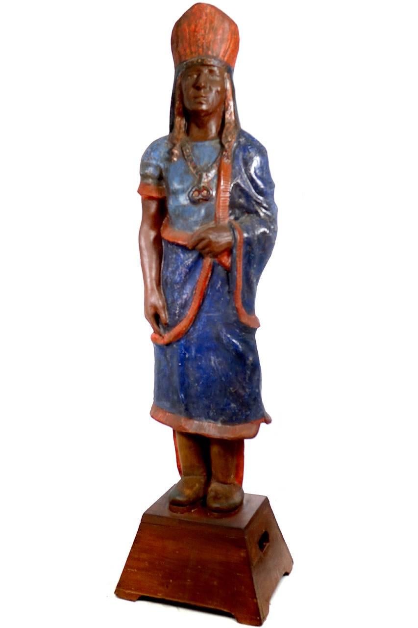 I'm guessing that this is a cigar store Indian. It's not holding cigars but must be an early advertising display. It looks to be very early 20th century. It has had some paint touch up and restoration over the years but still shows a good deal of