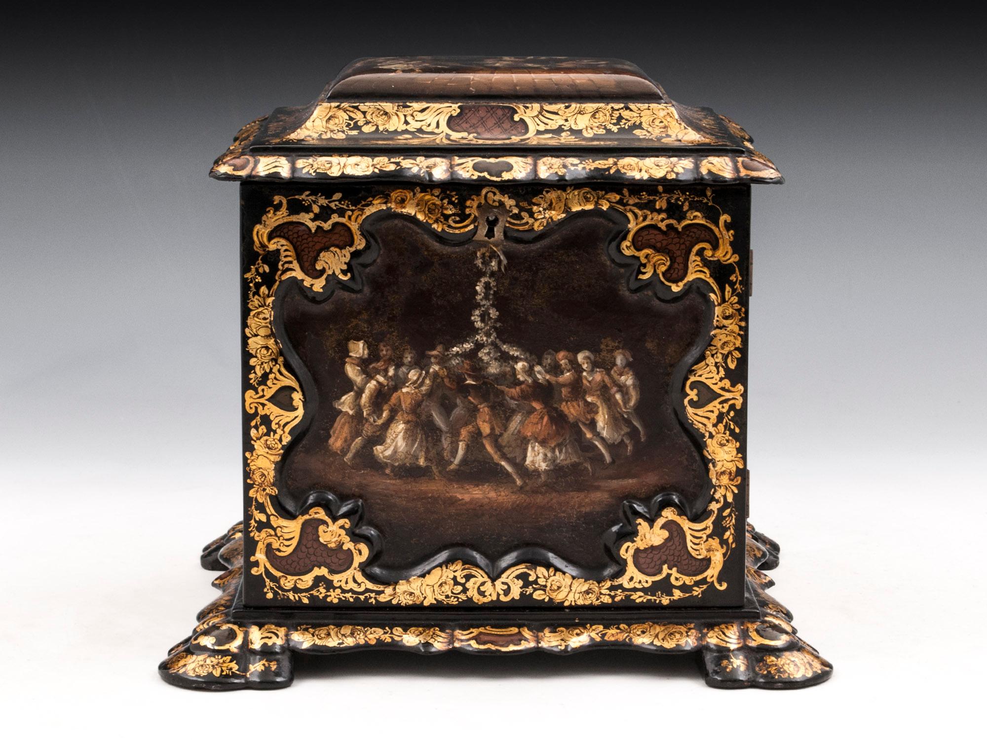 Papier mâché jewelry cabinet. Decorated with floral gold leaf framing expertly painted scenes of Maypole dancing to the front and top. The sides have further painted panels, one of a mother and child, the other of a lady at work. The door has an