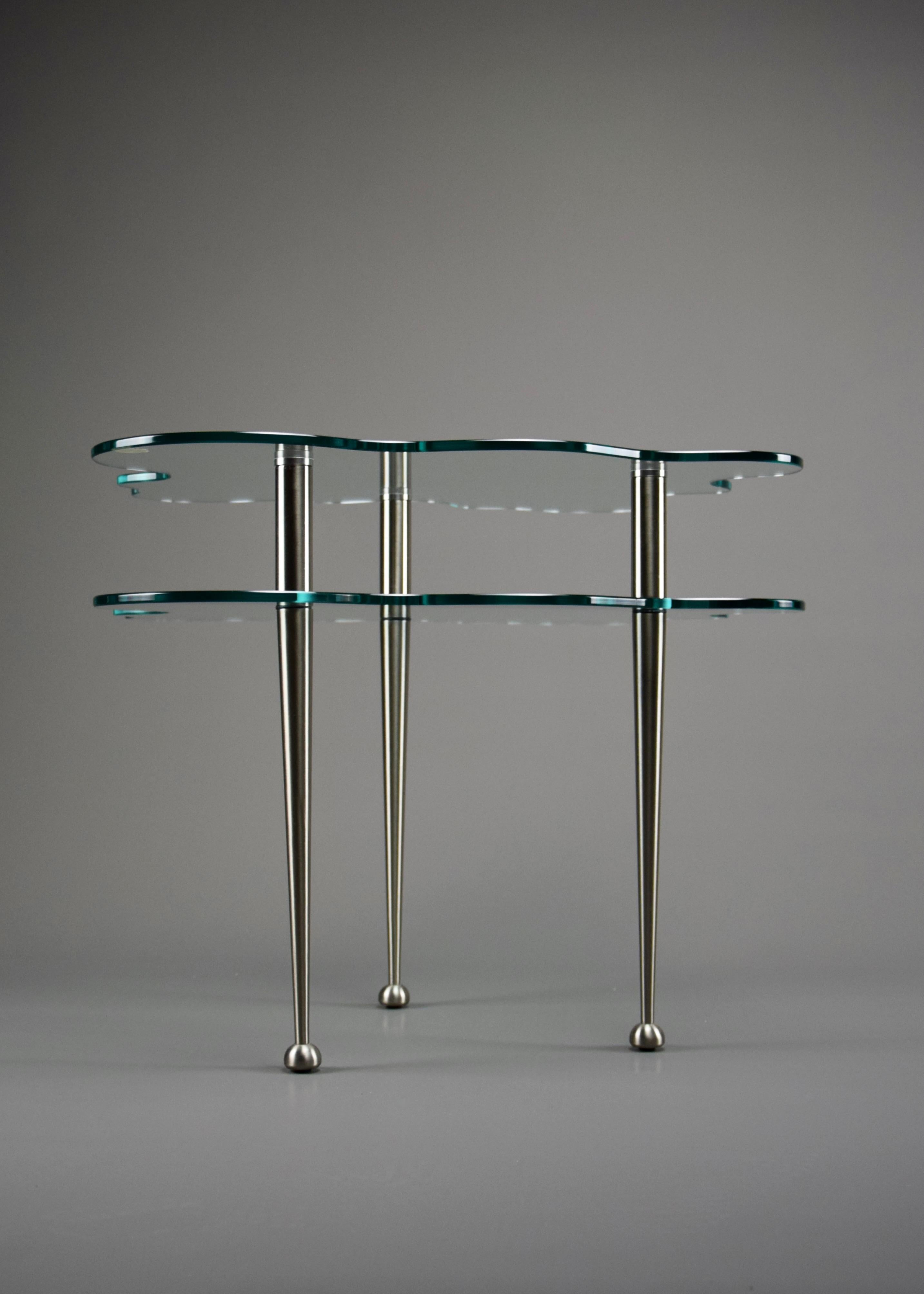 Elevate your space with these exquisite postmodern two-tier glass side tables, a rare and iconic design by Alessandro Mendini, one of the most influential figures in modern design. These tables, part of the Nuova Alchimia Collection from the 1980s