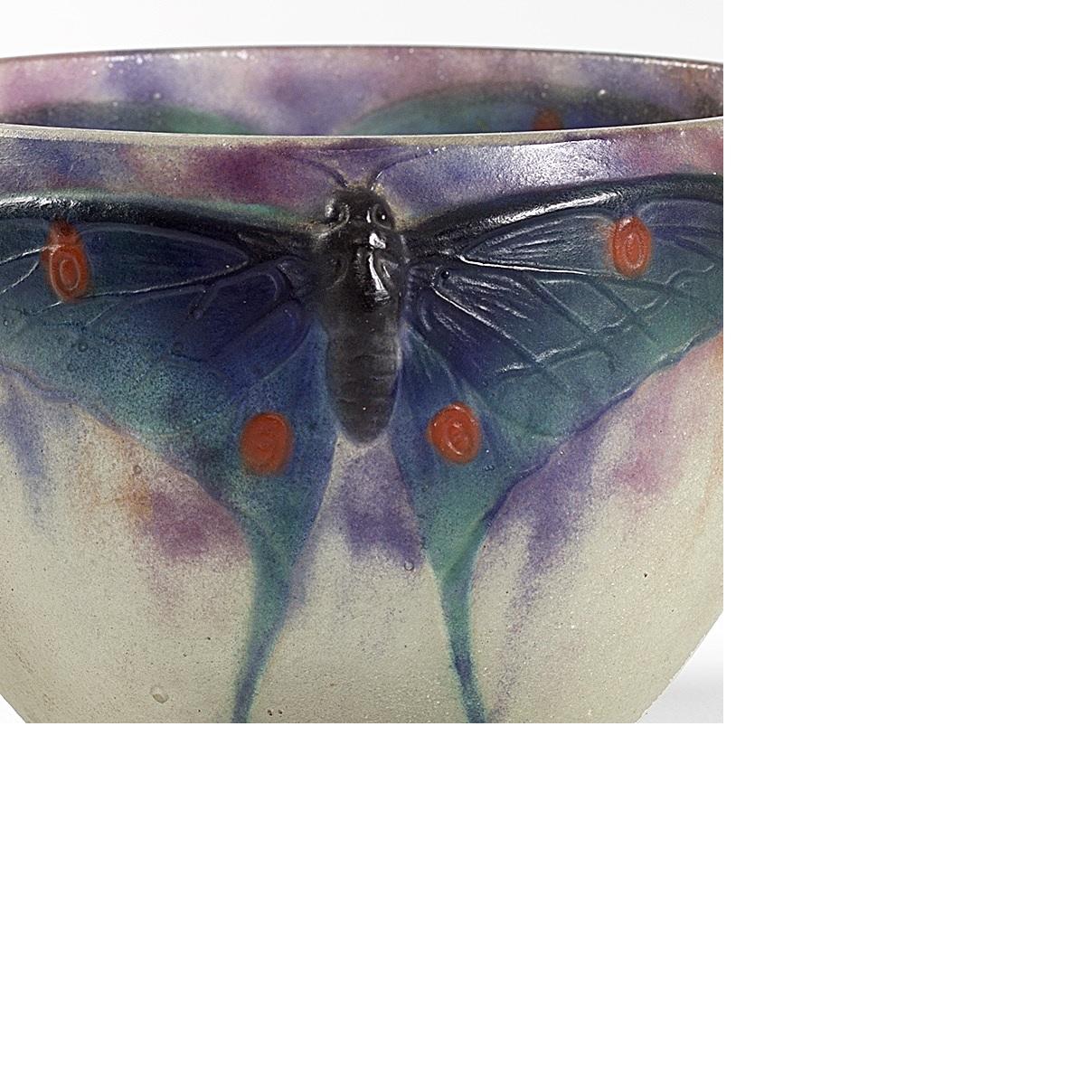 A French Art Nouveau pâte de verre “Papillon” bowl by Gabriel Argy-Rousseau. The bowl has three Luna moths with brown bodies and textured green wings with red spots. They sit just below the bowl’s rim in a background of mottled purple and pink,