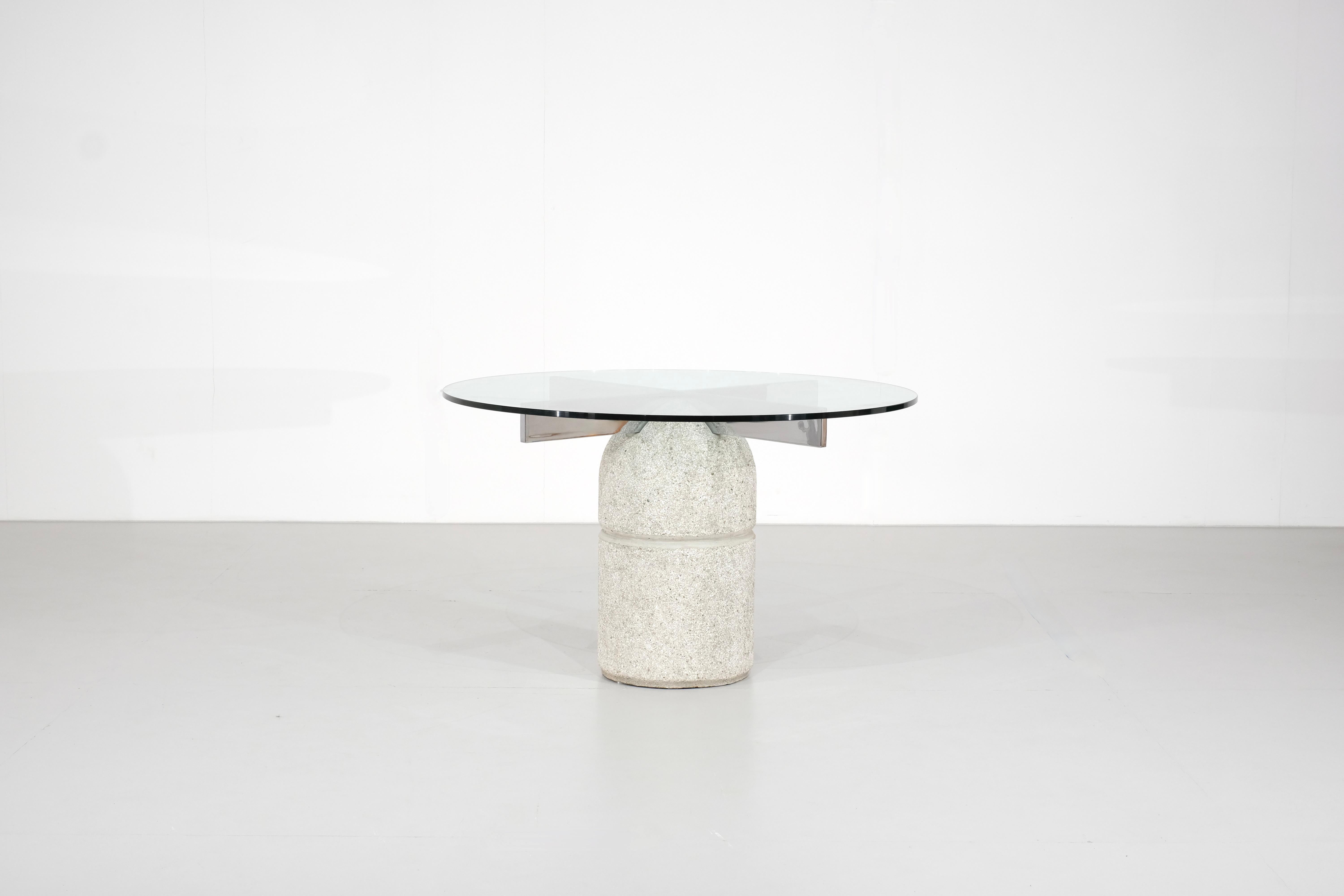 Mesa de comedor escultural de cristal sobre una base de hormigón llamada 
