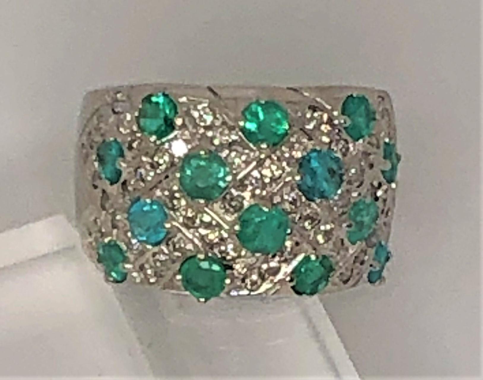 WOW- this unique ring is beautiful!  
14 karat white gold band approximately 5mm graduating to 14mm
14 round prong set paraiba tourmaline and emerald stones set in among diamonds
Approximately size 7.5
Stamped 