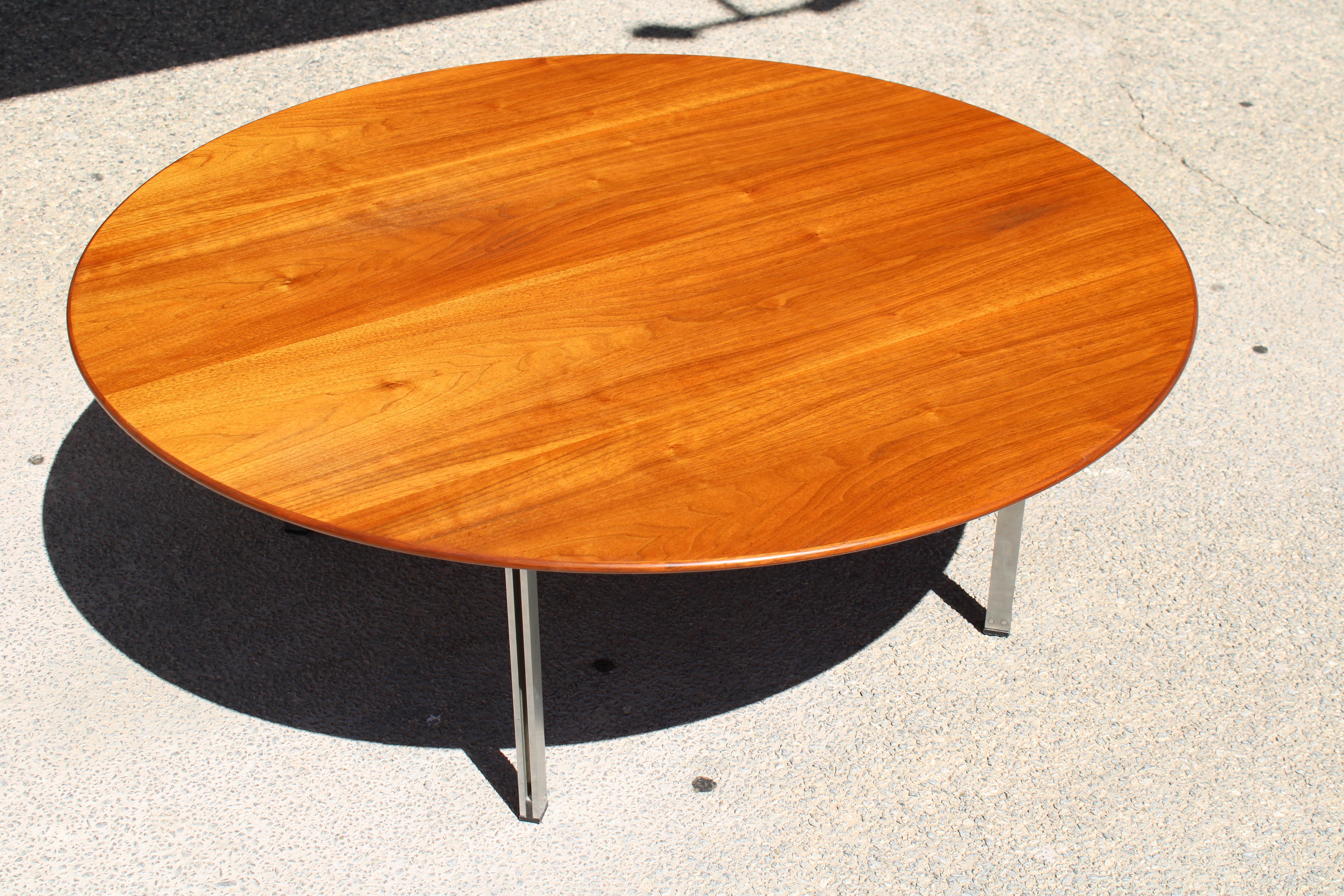 Florence Knoll a conçu cette table basse circulaire pour Knoll, faisant partie de la série Parallel Bar, produite de 1955 à 1968, modèle 404. Son plateau en noyer est soutenu par quatre pieds en acier inoxydable qui présentent la forme de barres