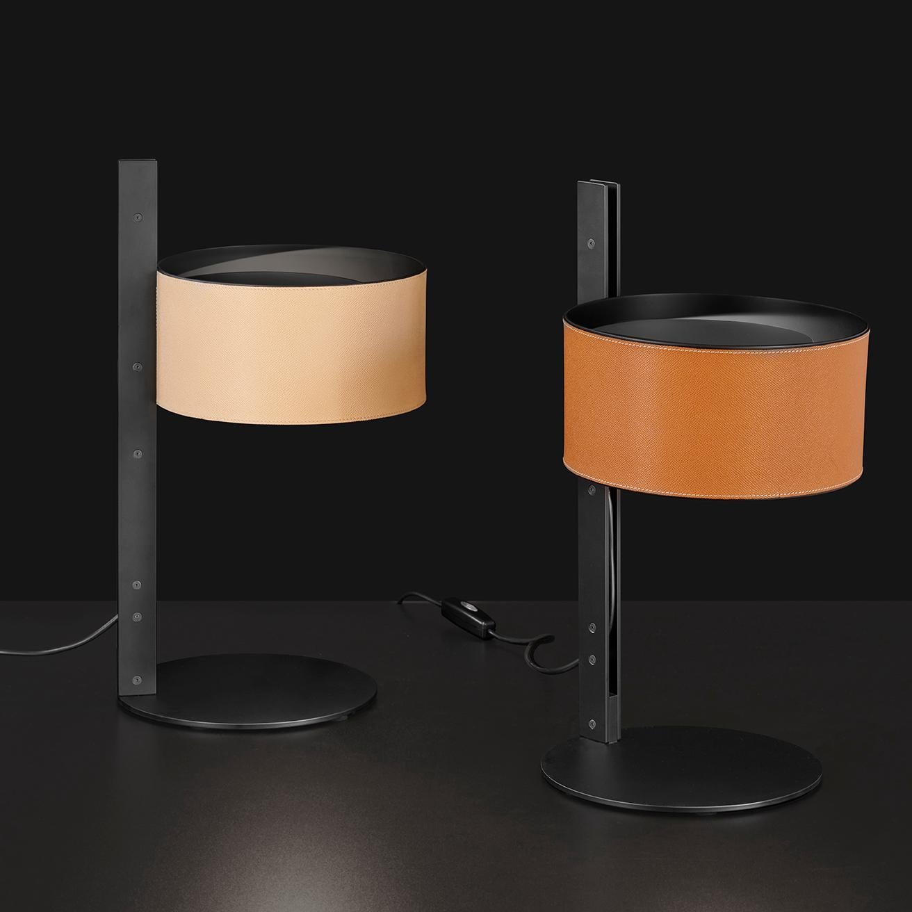 Die von Victor Vasilev entworfene Tischleuchte Parallele besteht aus einem zylindrischen Lampenschirm aus Metall, der von einem seitlich angeordneten vertikalen Stiel getragen wird. Der Stiel besteht aus zwei mattschwarzen Metallplatten, die im