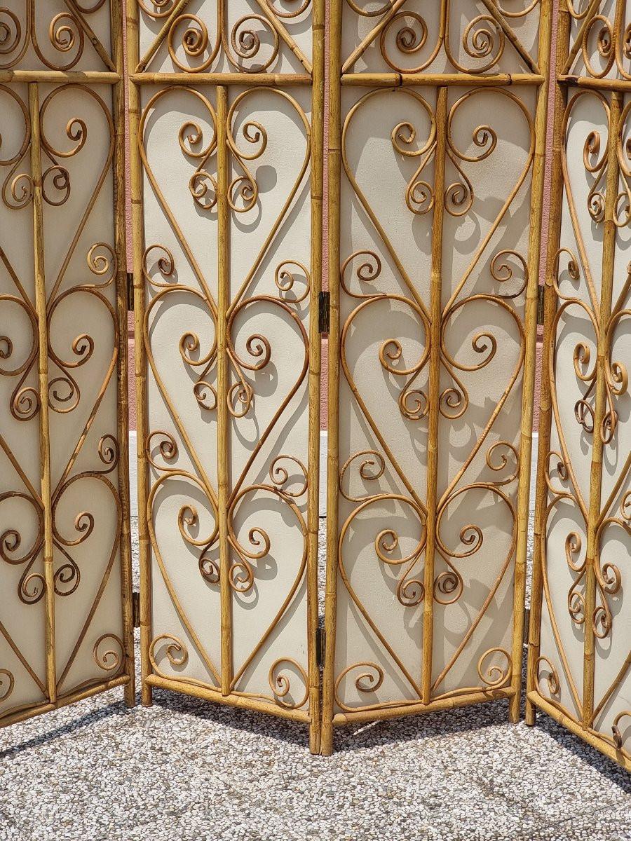 Paravento decorativo a quattro pannelli realizzato in bambù e rattan, databile intorno agli anni 1950. L’elemento distintivo è il disegno ornamentale ottenuto con intrecci e curvature a spirale del rattan, tecnica tipica dell’artigianato tropicale