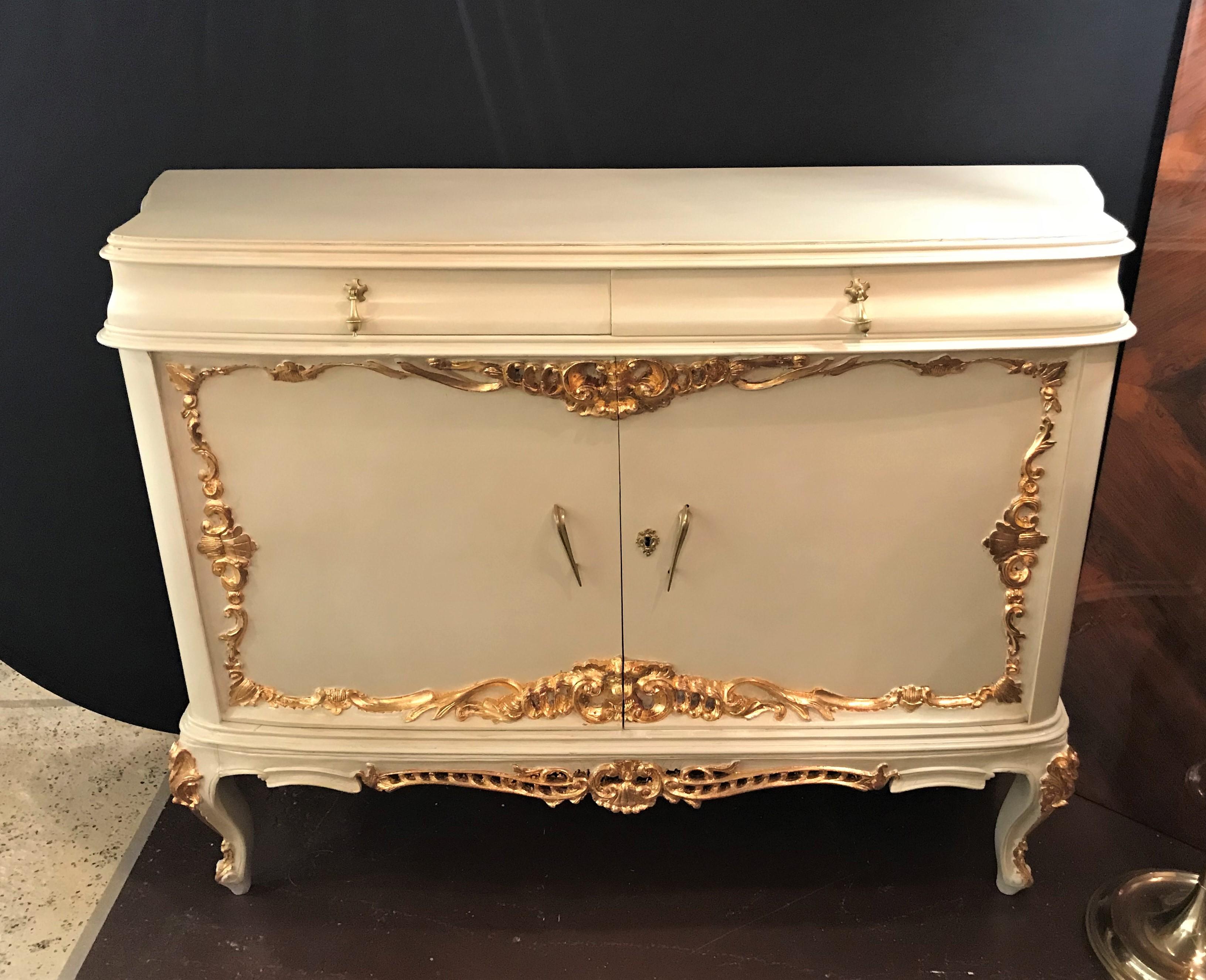 A parcel-gilt and paint decorated two-drawer and two-door Louis XV style cabinet. This antique cabinet has recently been painted and given gilt gold hand high lights to accentuate the overall look. Fine quality and a great finish.