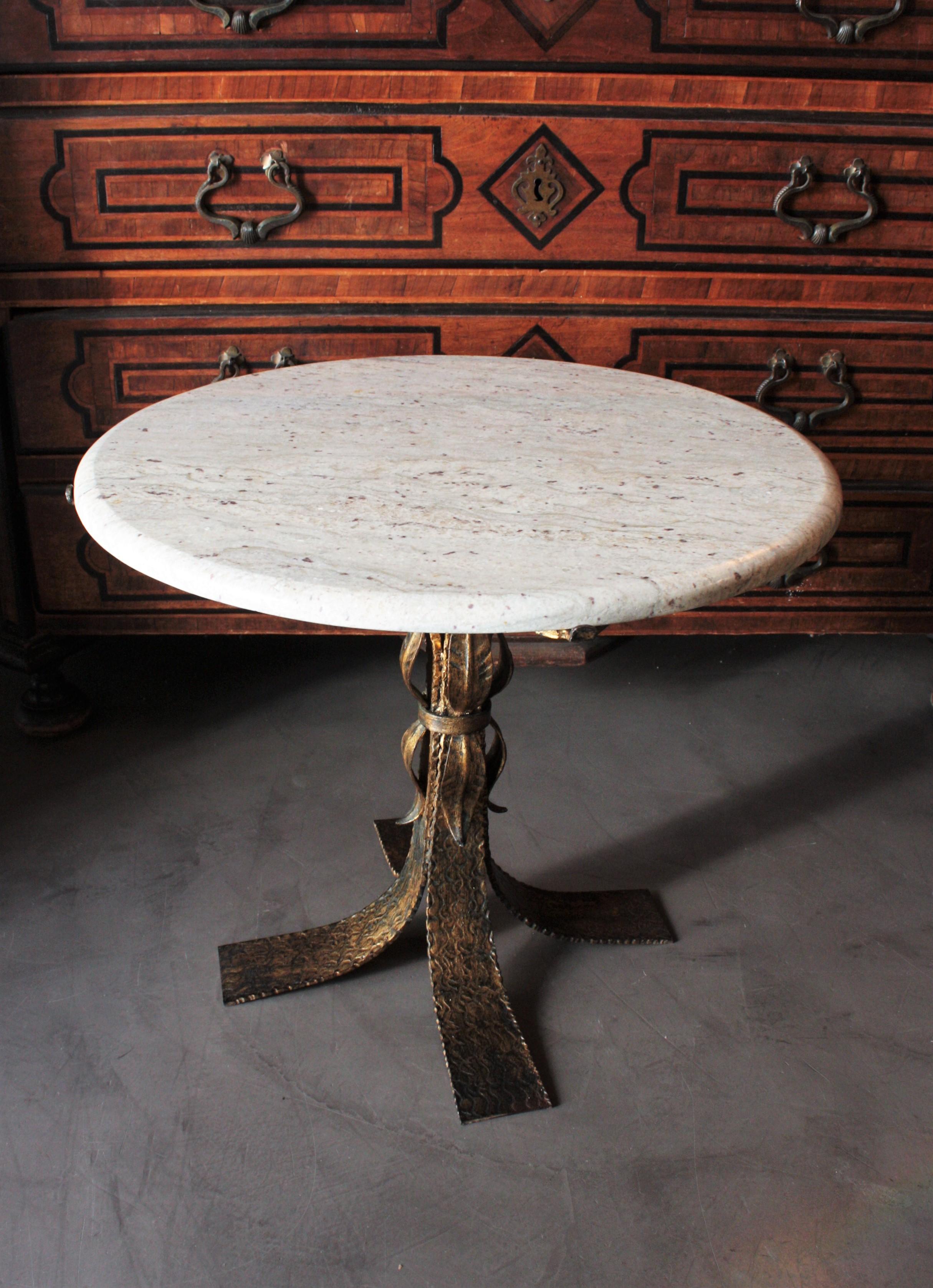 Eye-catching Mid-Century Modern gilt wrought iron low table with round white marble top. Spain, 1950s.
This side table has a beautiful spotted white marble top standing up on a wrought iron four feet base with leaf details. It retains rests of its