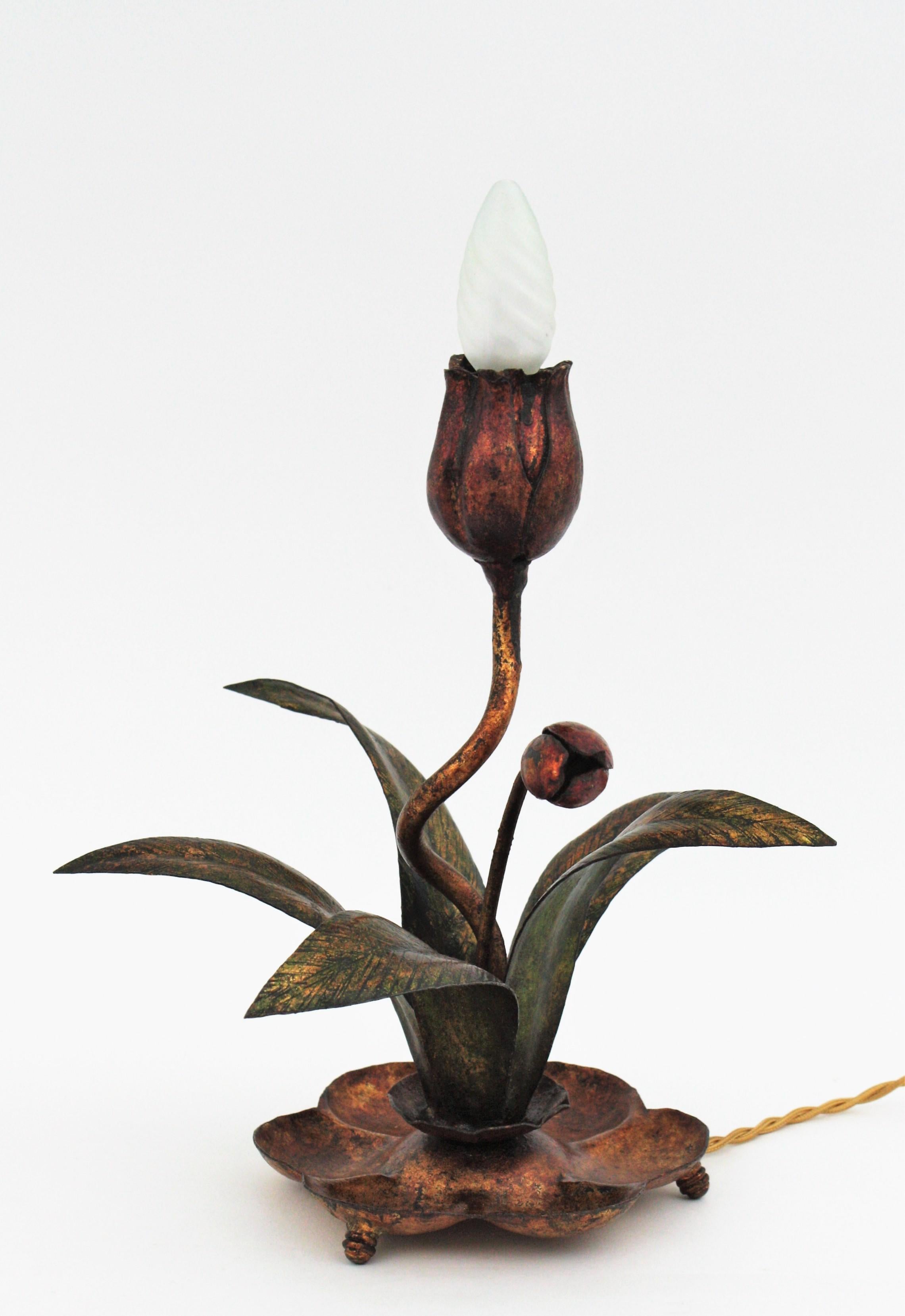 Eye-catching Polychomed gilt metal floral table lamp, Spain, 1930s.
This table lamp features a standing up red flower holding a bulb. The flower is raising up from a plant with green leaves. A small flower bud completes the lamp.
This lamp has a