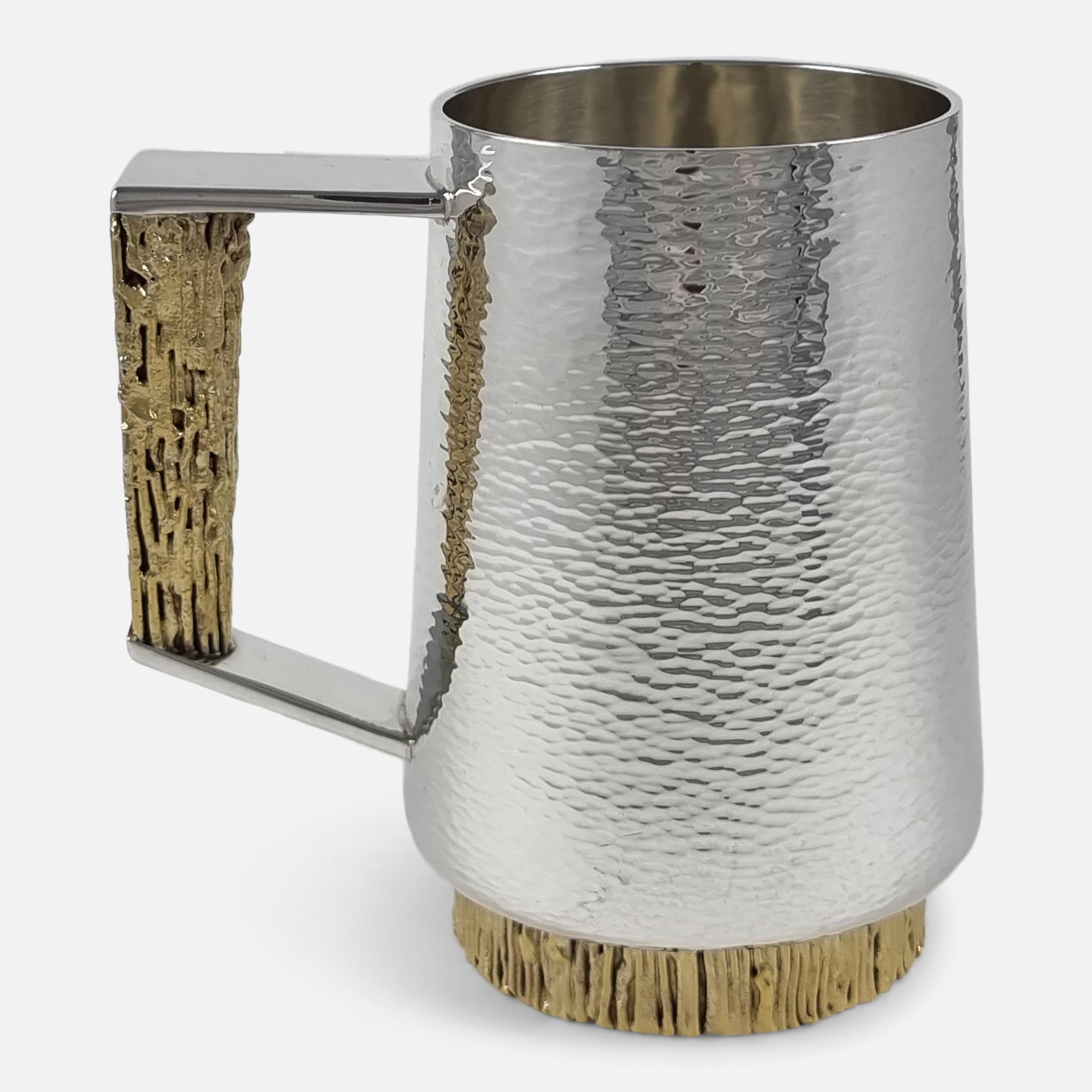 An Elizabeth II parcel-gilt sterling silver mug by Stuart Devlin, London, 1974. The mug is of tapering circular form, with textured decoration, angular scroll handle with gilded textured decoration, on a textured gilded foot.

Assay: - .925 Sterling