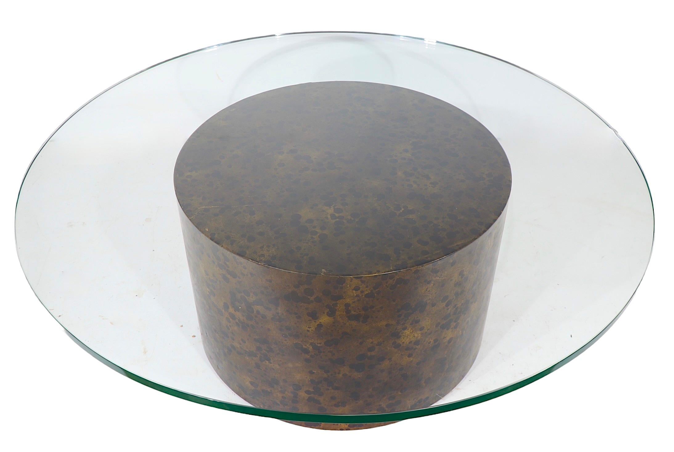 Voguish, chic and sophisticated coffee table having a faux metal finish pedestal base composed of parchment paper over wood, which supports the original thick ( .75 in. ) round glass top. The table is reminiscent of the work of Aldo Tura, this