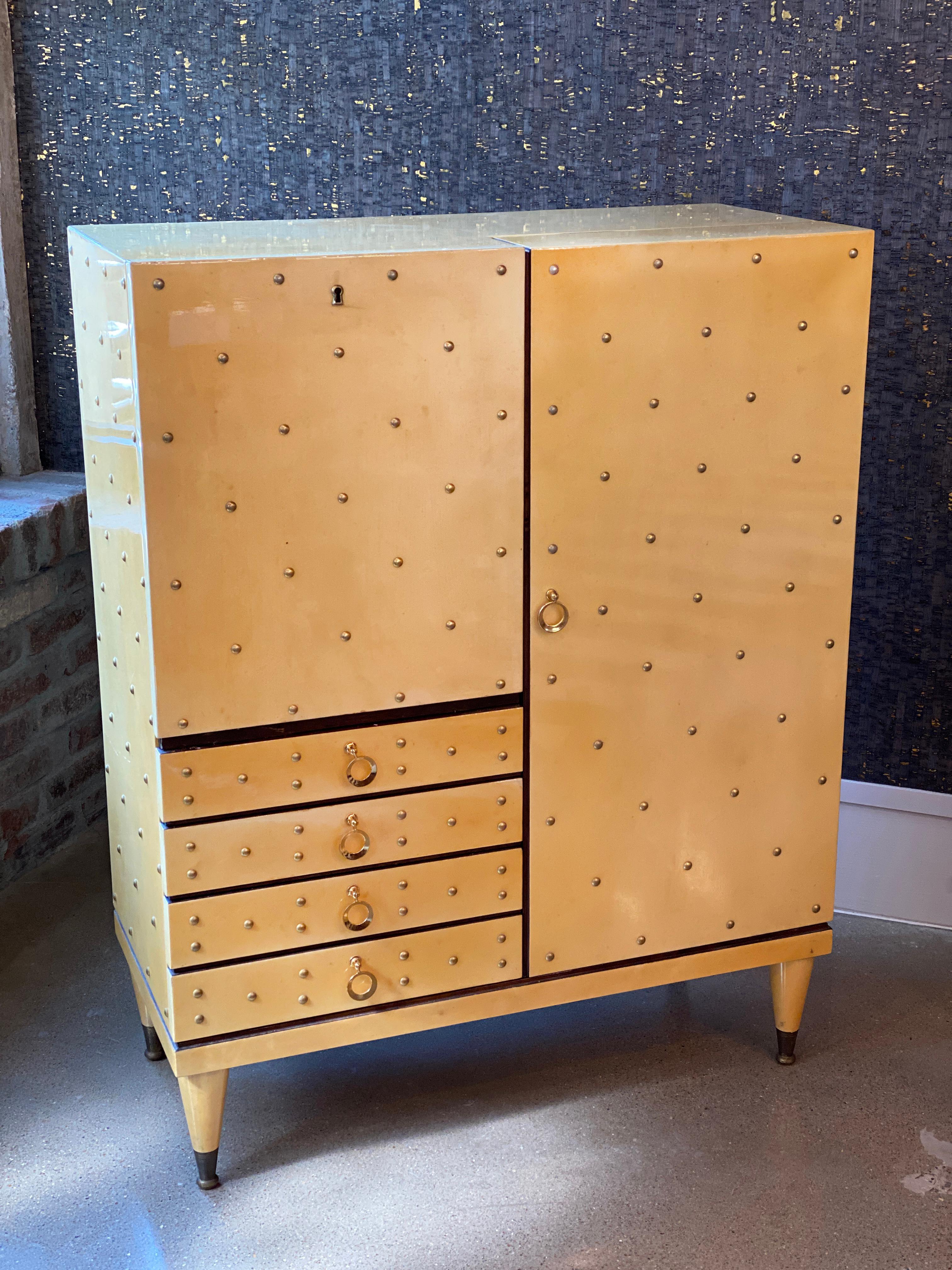 Lacquered goatskin parchment bar cabinet by famed maker, Aldo Tura. Includes cabinet storage, drawer, and drop down surface with mirrored interior. Fine brass hardware and trim. Considered European Mid-Century Modern but with a Hollywood Regency