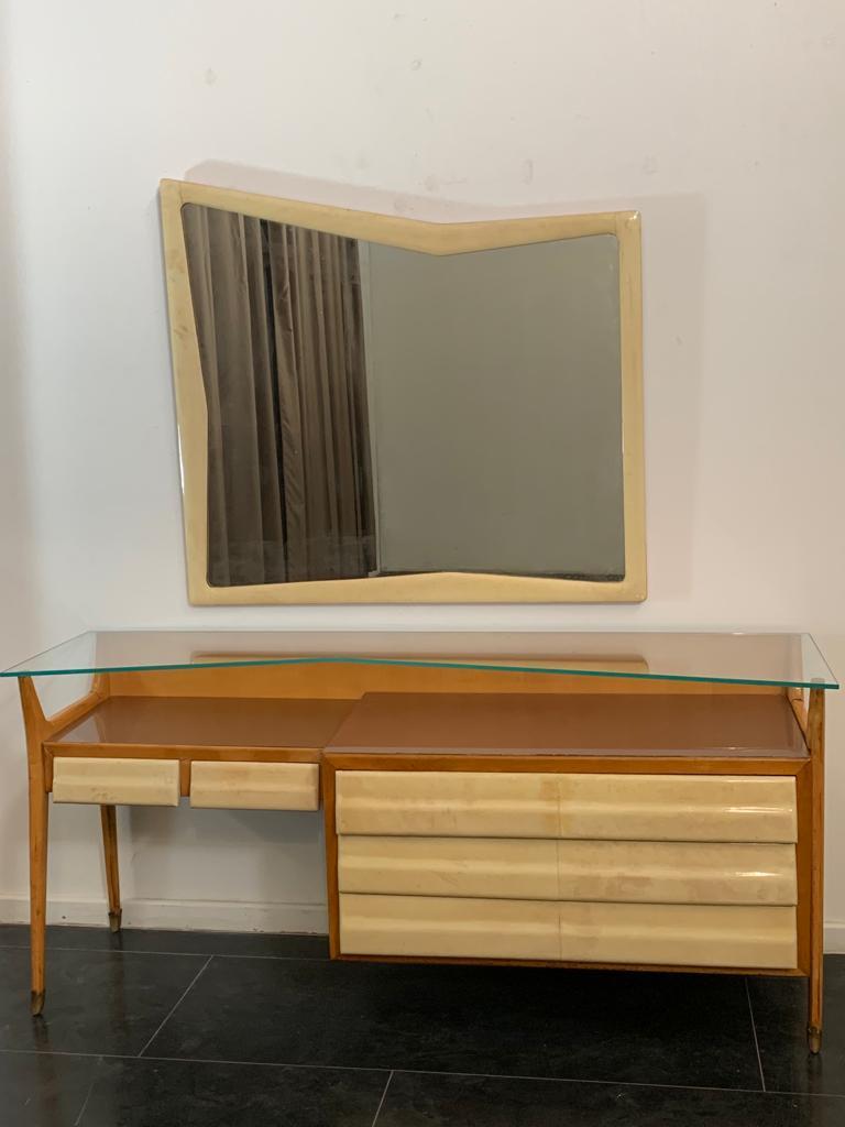 Dresser and mirror in the style of Silvio Cavatorta's early work, 1950s. 
The first one is made of maple with parchment drawers, brass tips, a dark mauve glass plate placed on the top, and a crystal upper shelf; the second one is in parchment. Both