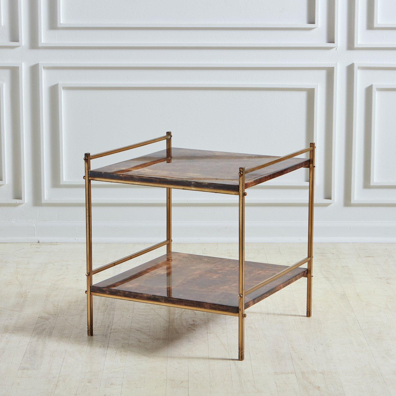 A vintage Italian two-tier side table in the style of Aldo Tura. This table has a sleek patinated brass frame and two square shelves with a lacquered parchment finish in a deep brown hue with subtle color variations. Sourced in Italy, 20th Century.


