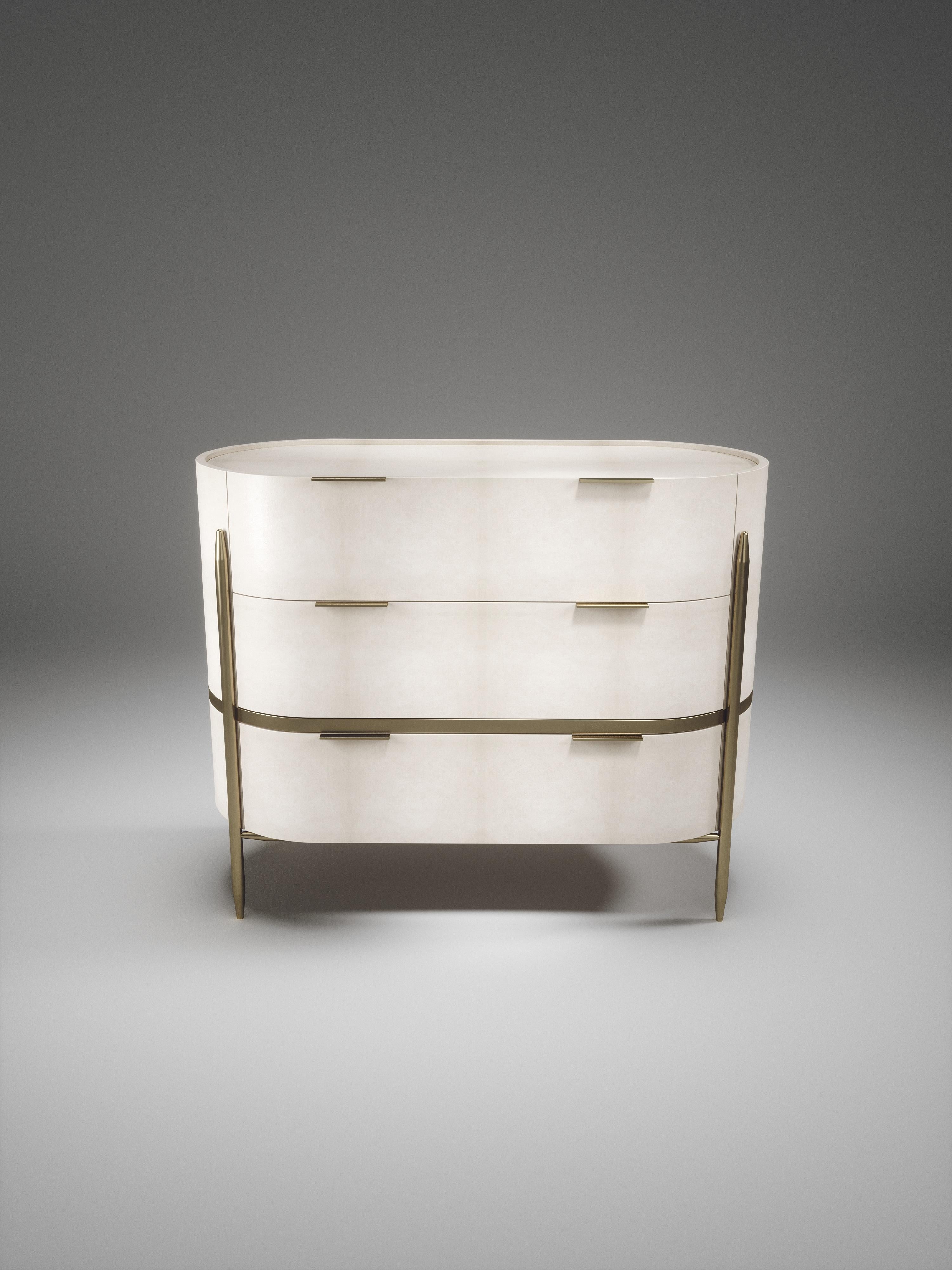 The Dandy oval chest of drawers by Kifu Paris is an elegant and a luxurious home accent, inlaid in cream parchment with bronze-patina brass details. This piece includes 3 drawers total and the interiors are inlaid in gemelina wood veneer. Available
