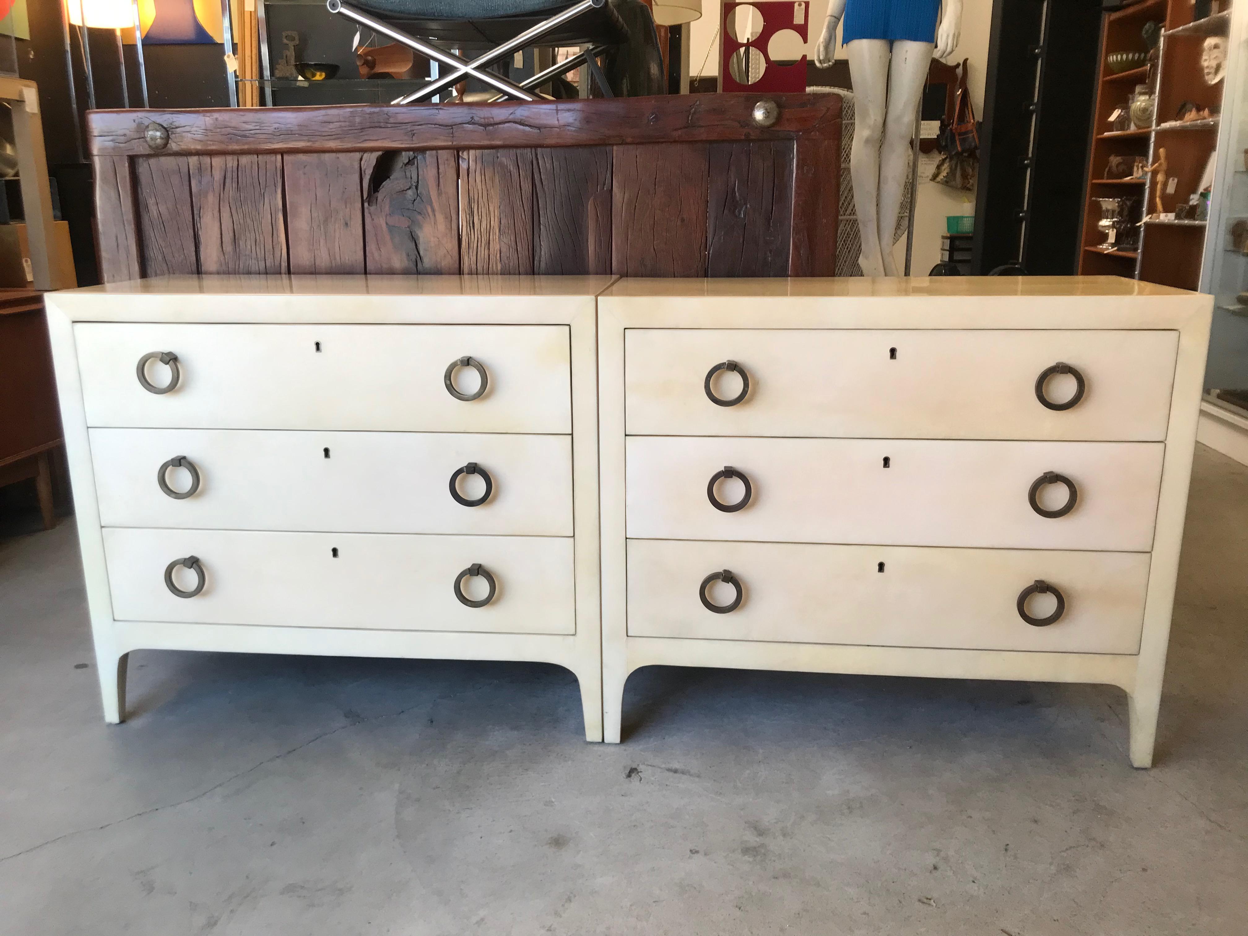 Elegant and handsome pair of dressers.
Ultra modern designs.
Quality construction.
Mahogany wood covered with goatskin / vellum veneer. 
Clean lines in a beautiful ivory hue. 
Circular bronze pulls.
Fine original condition with a nice patina.
Great