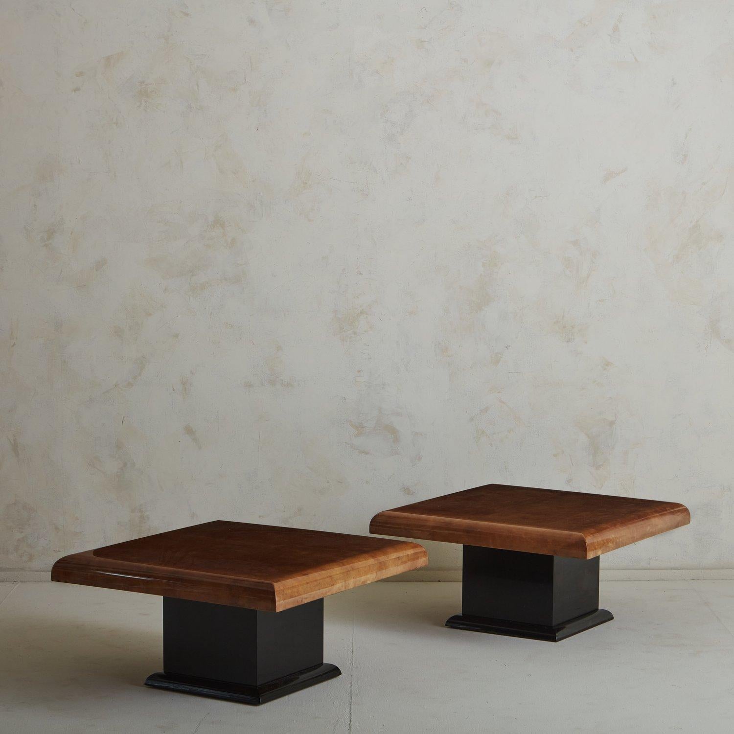 Une superbe table basse dans le style d'Aldo Tura, avec une finition parchemin laquée cognac. Il présente un épais plateau carré aux bords arrondis et repose sur un piédestal carré laqué noir avec une garniture en bandeau. Nous adorons les motifs