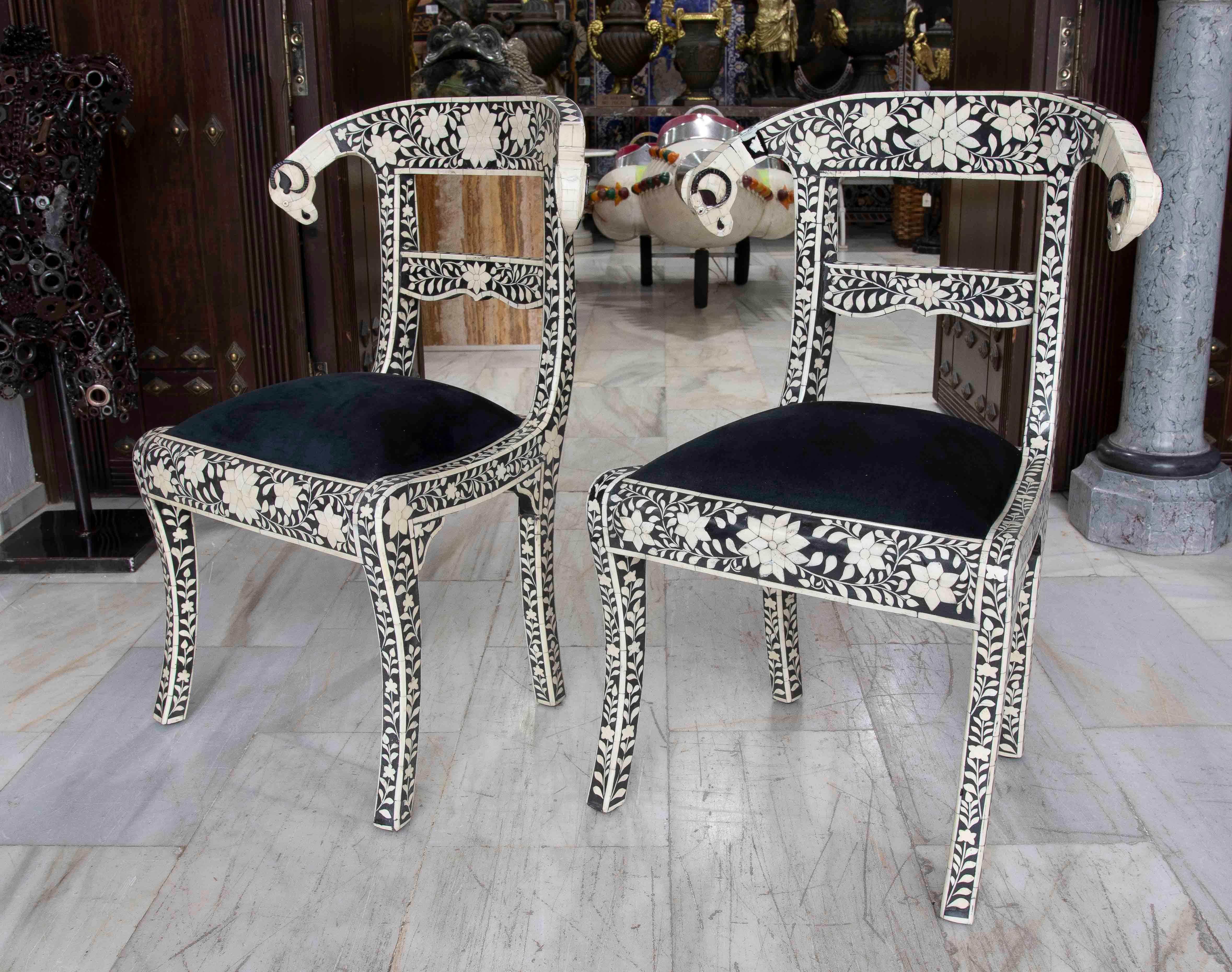 Élégante paire de sillas décoratives portées à la main, avec un exquis travail de marqueterie en blanc sur fond noir, qui forme de délicats motifs floraux. Les montants présentent des formes incurvées avec des terminaisons en volutes hautes, des
