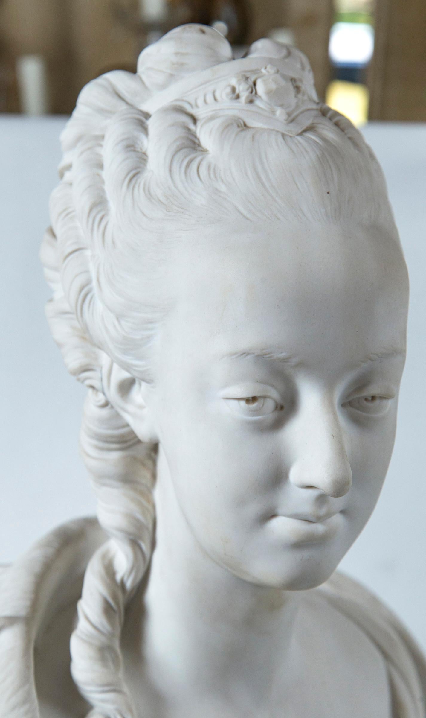 Possibly a bust of Madame du Barry. Signed across the back Pajou. A round seal next to the signature is inscribed Nationale Sevres Manufacture, with letters and number below. There is no Sèvres mark that we can find. She wears a outer garment that