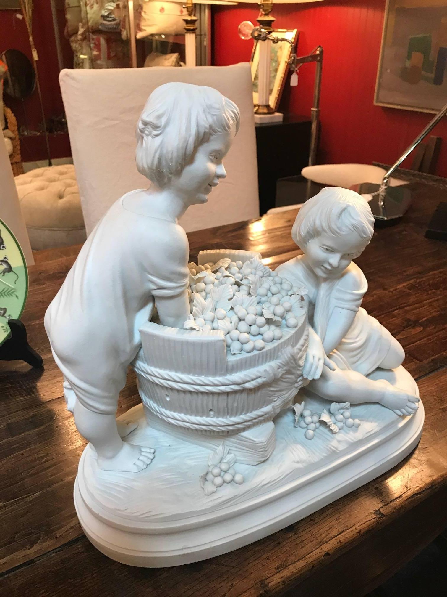 A French Parian porcelain sculpture of children with a basket of grapes. Marked made in France on underside and Artist-signed on the top of the base, mid 20th century.