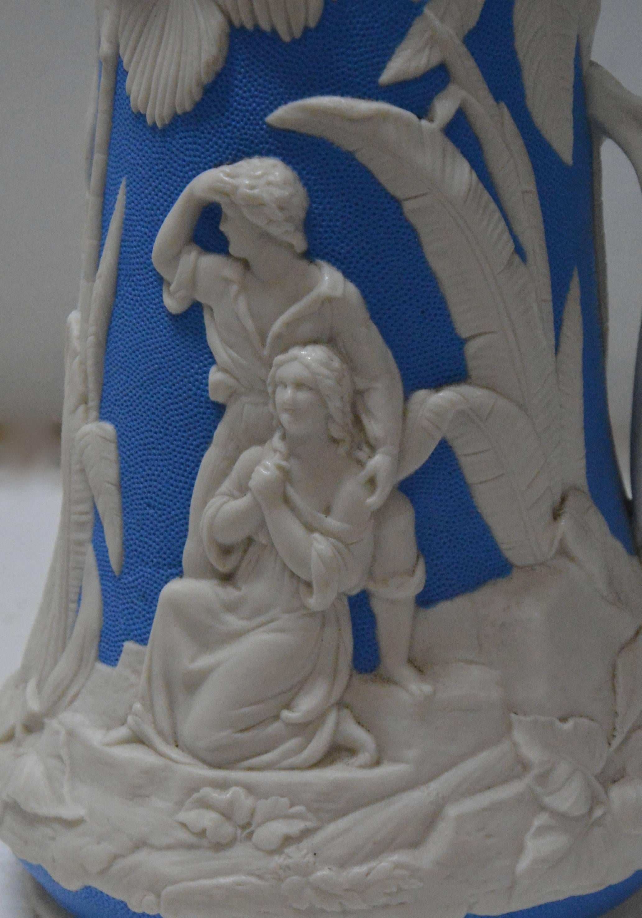 A beautiful molded earthenware pitcher made by the Jones and Walley Co. of Cobridge, Stoke-on-Trent, England. The piece features people in a tropical scene. The vibrant blue and white are done in high relief with amazing details. The pitcher is