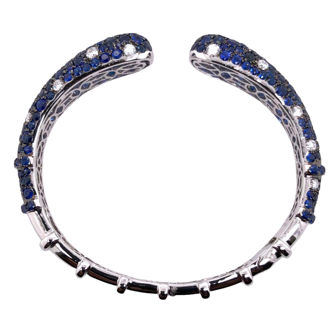 PARIS Craft House Sapphire Diamond Cuff. Crafted in 18 Karat White Gold, this cuff features 12.71ct of hand selected matching Sapphires, accompanied with 2.20ct Round Diamonds. While the bangle is made of 18 Karat White Gold, these prongs are plated