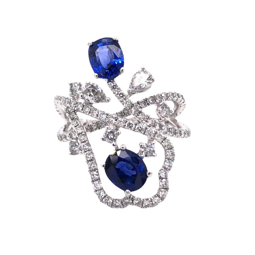 PARIS Craft House Sapphire Diamond Hoop Earrings. Featured in this article are 2 mystic Sapphires carved in Oval cuts. Crafted in 18 Karat White Gold, these blue stones are adorned with Diamonds of different cuts and sizes. These stones are lined