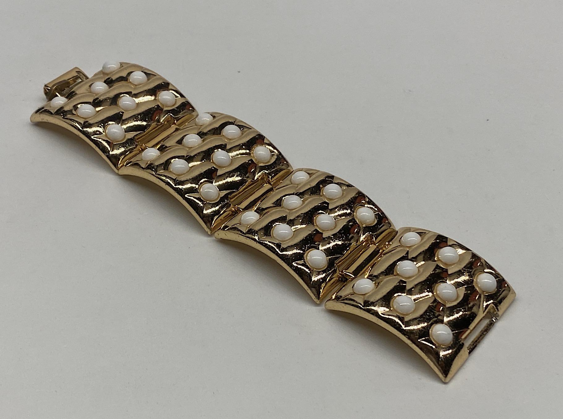 A vintage 1950s wide four panel bracelet by French fashion jewelry company Oranium in Paris. Each of the four panels have a diamond pattern quilt design set with white glass cabochon. Additionally, the panel links are curved so the bracelet will fit