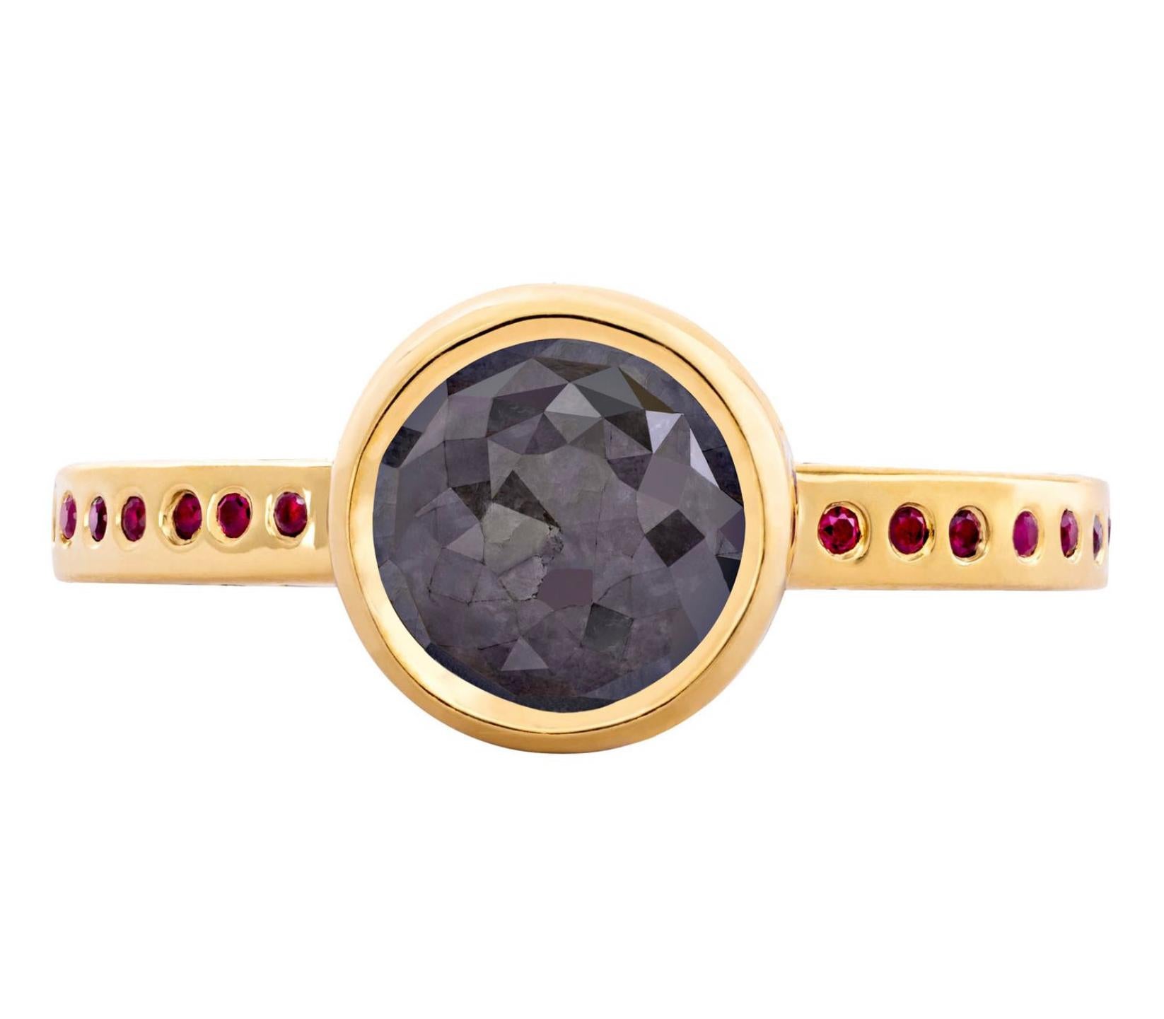 From the Tale of Five Rings Collection, this 22K gold ring has a stunning 3.24 carat natural black rose cut diamond center stone with .9mm red rubies surrounding the center stone bezel and top of ring band, .8mm grey diamonds surrounding sides the