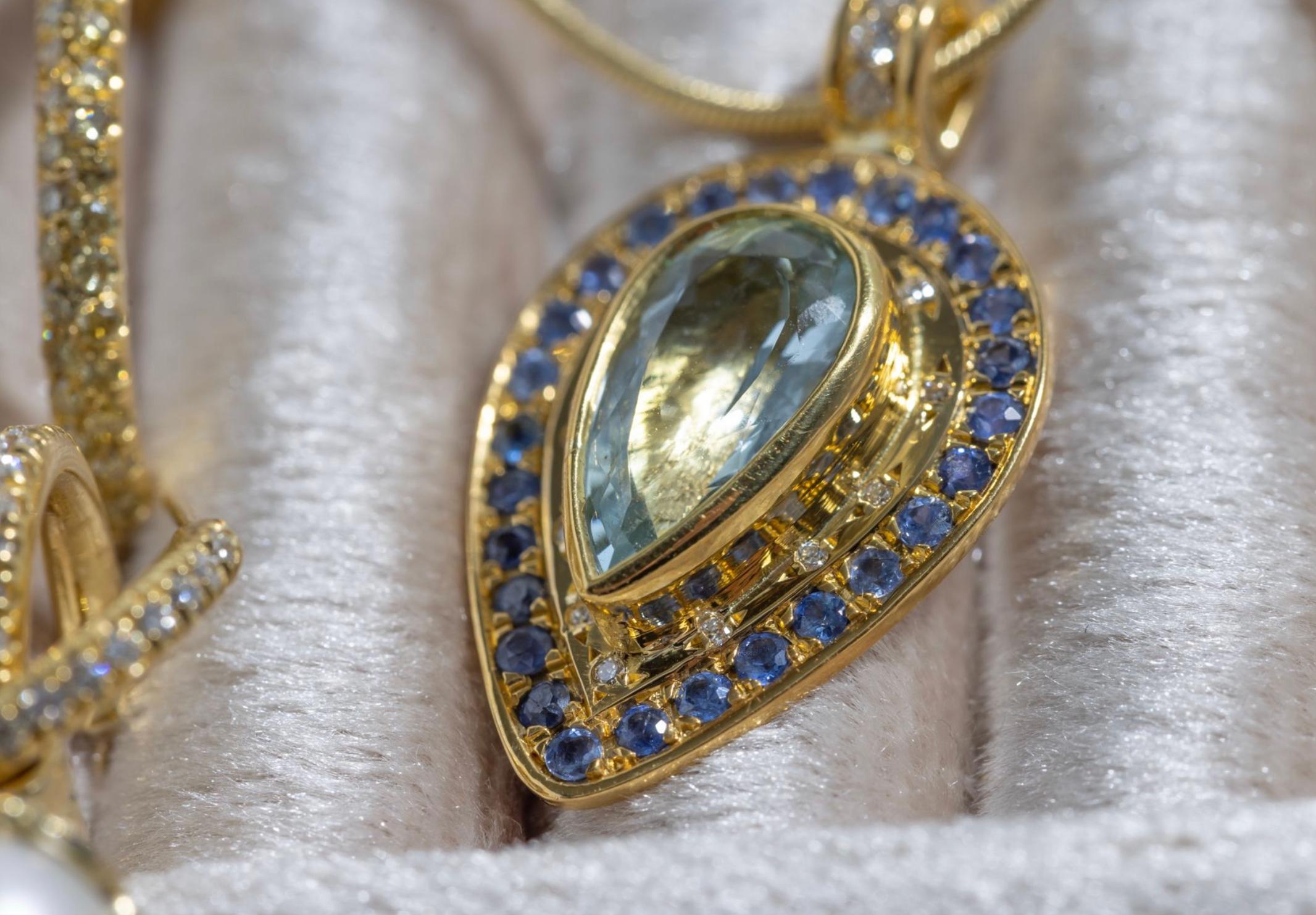 Paris & Lily one-of-a-kind, handmade, 22K gold, aquamarine, sapphire and diamond pendant. The pendant is approximately 24mm in length from the bail to the tip.  The pendant features a pear shaped aquamarine surrounded by diamonds and a border of