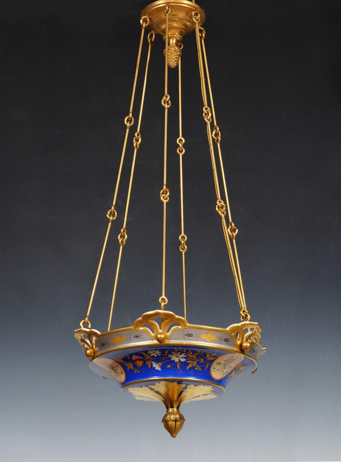 Charming painted porcelain chandelier with a blue background, in the shape of a basin with a flared and openwork border decorated with foliage on a platinum background alternating with golden rosettes. The body is decorated with a rotating