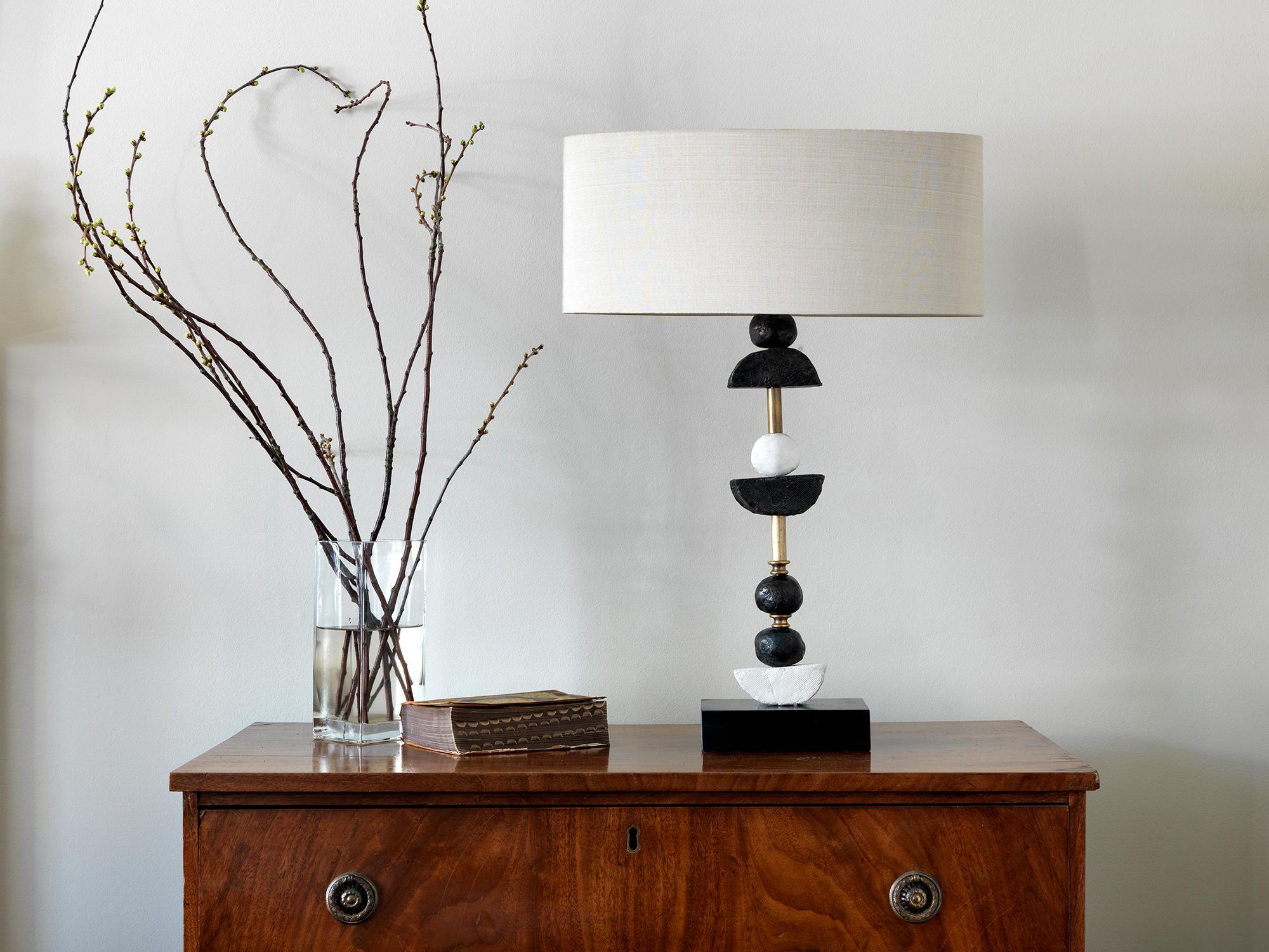 This contemporary Margit Wittig table lamp is mounted on a slate base and features multiple bronze and white resin handcrafted spheres with semi-circles. Each element is hand patinated to increase tonal contrast and enhance the surface